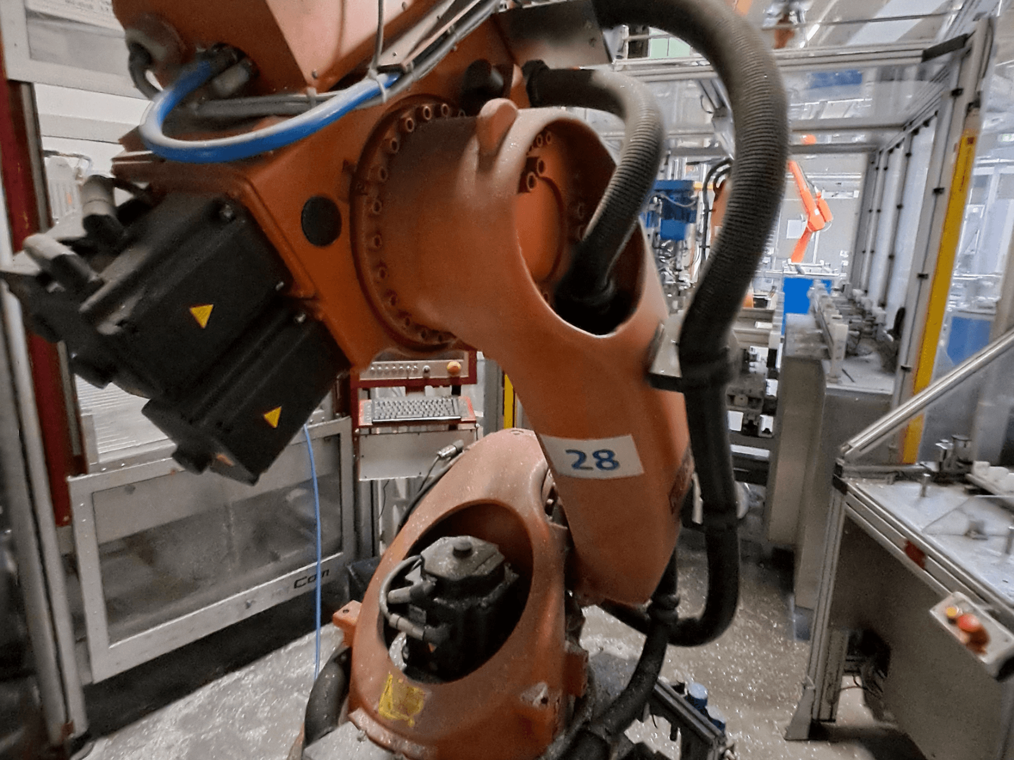 Närbild på robotarmen KUKA KR30-3, med orange kropp och märkt med siffran 28, som visar motorer och kabeldragning sett från sidan.