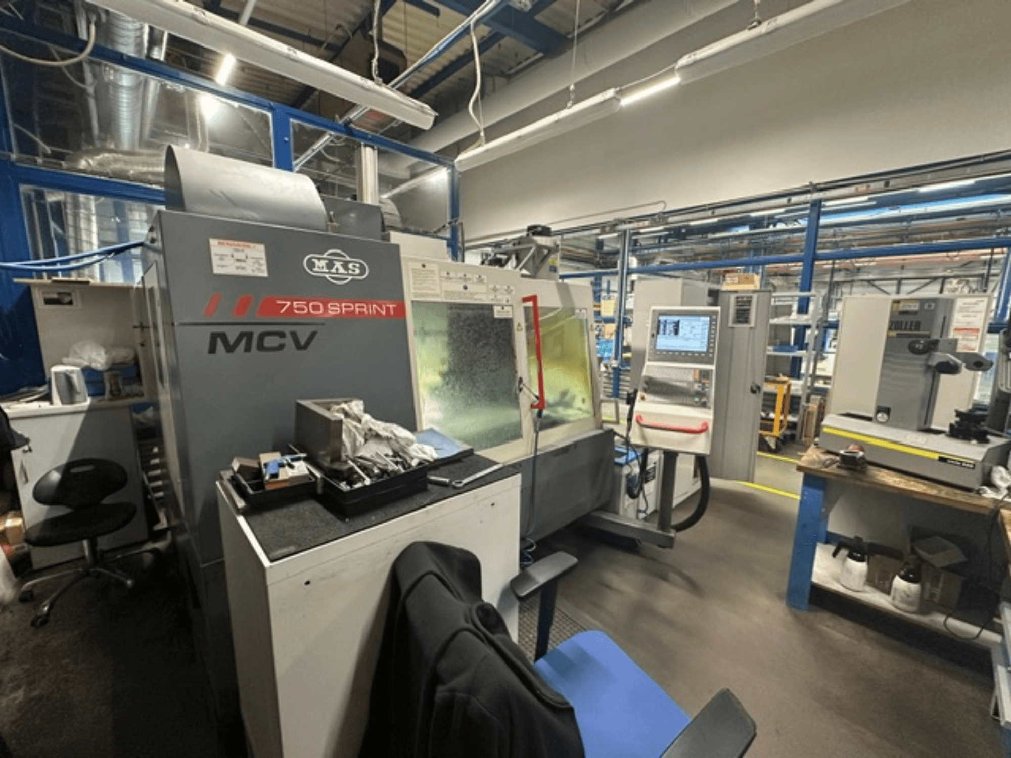 Det vertikala bearbetningscentret KOVOSVIT MAS MCV 750 Sprint i en verkstad, där kontrollpanelen och arbetsområdet visas i sidovy.