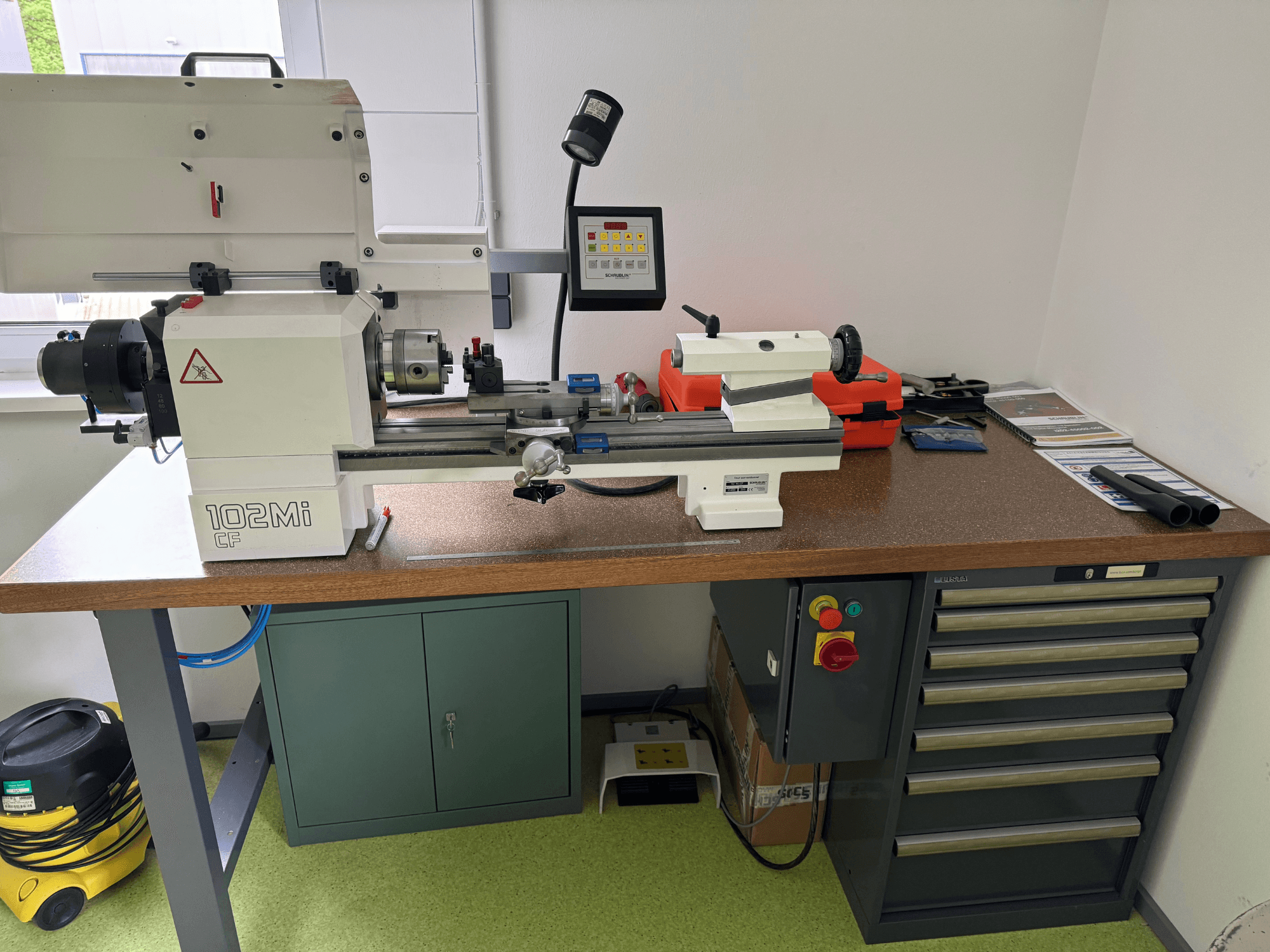 SCHAUBLIN 102Mi W25 horisontell svarv i en verkstad, framifrån med detaljer på kontrollpanelen och arbetsbänken.