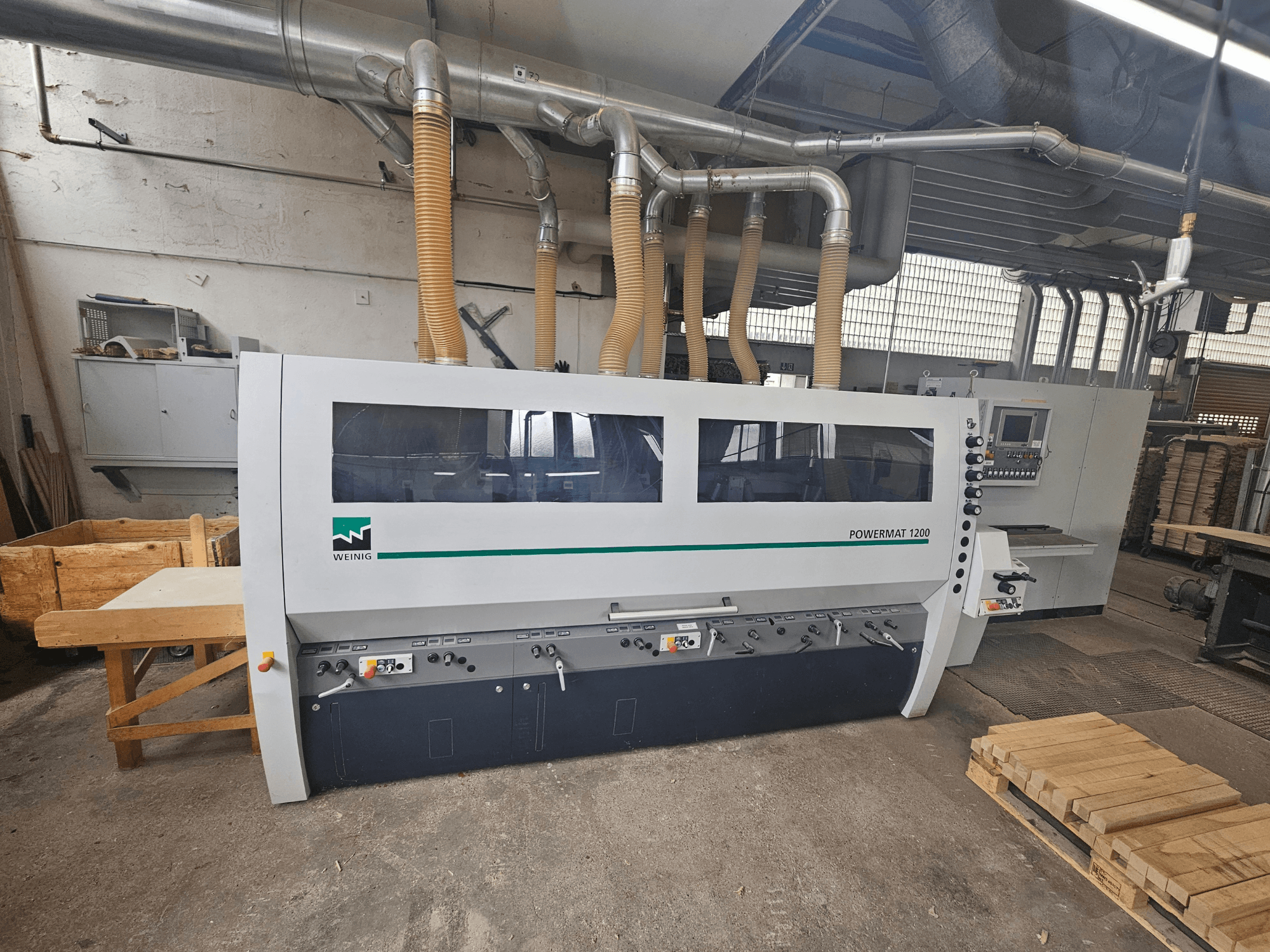Weinig Powermat 1200 träbearbetningsmaskin, framifrån, med kontrollpanel och vedstaplar i en verkstadsmiljö.