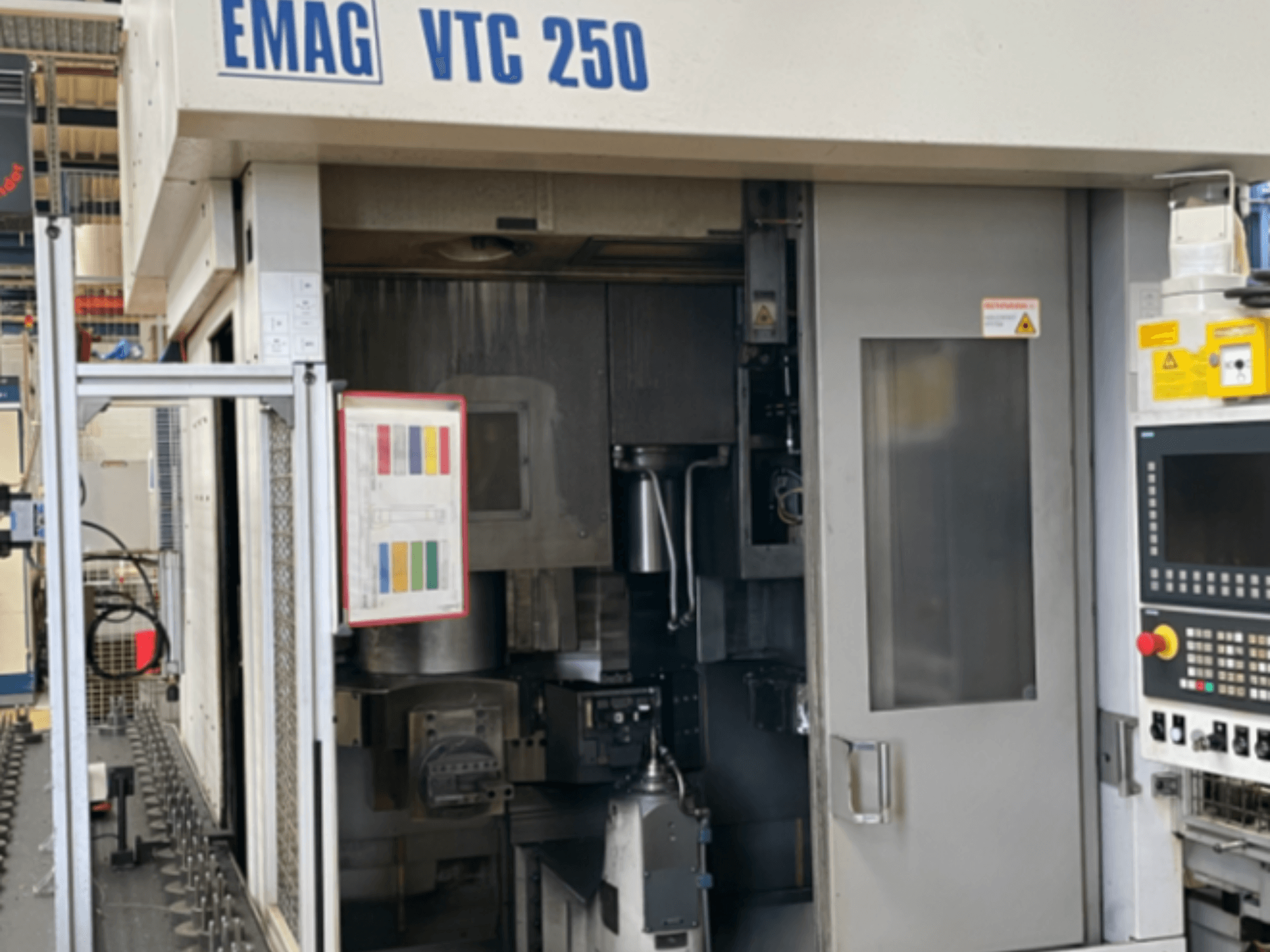 Framifrånvy av den vertikala svarven EMAG VTC 250, där man ser kontrollpanelen, användargränssnittet och den öppna luckan.