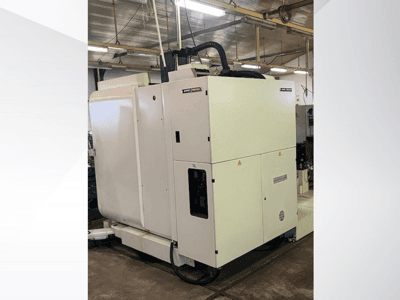 Vit CNC-maskin för industriellt bruk sedd framifrån, med kontrollpanel och ventilation, i verkstadsmiljö.