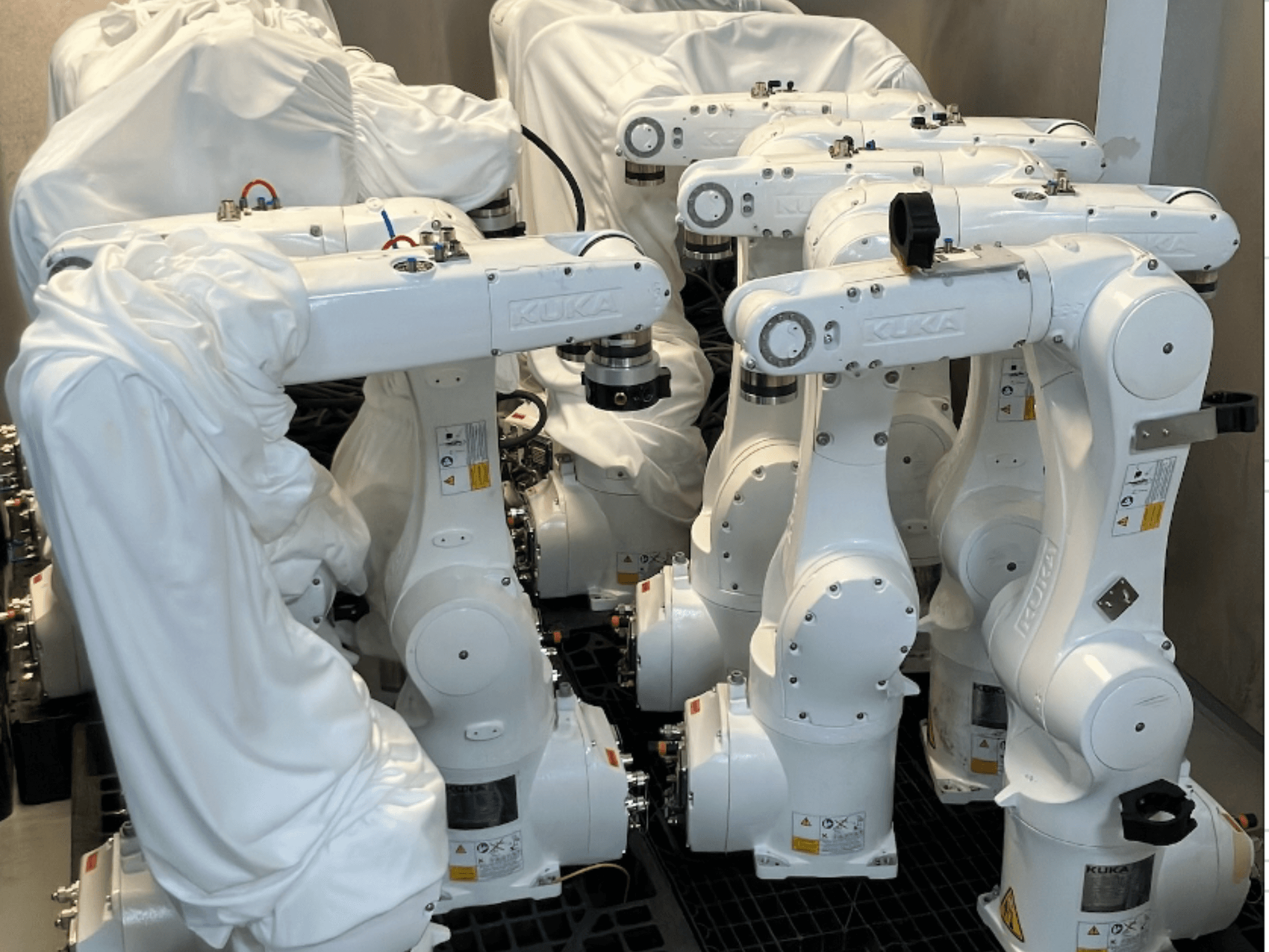 KUKA KR 10 R900-2 robotarmar klädda i vitt tyg, sett uppifrån, visar flera enheter i lager.