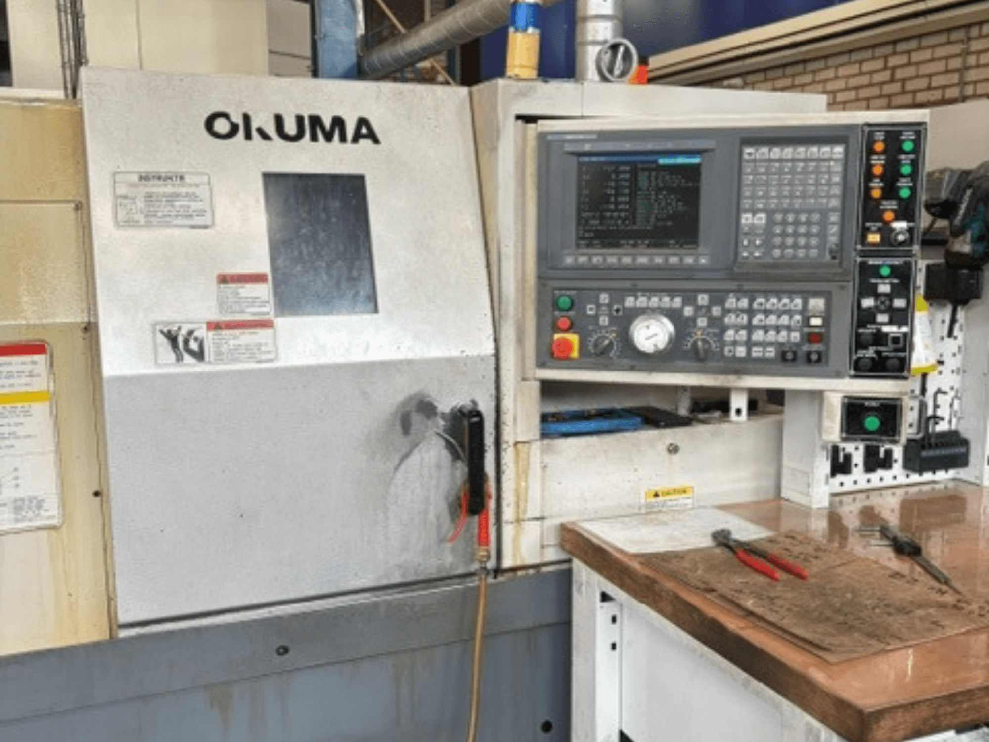 Okuma ES-L10II horisontell svarv, framifrån sett, med kontrollpanel, display och arbetsområde med verktyg.