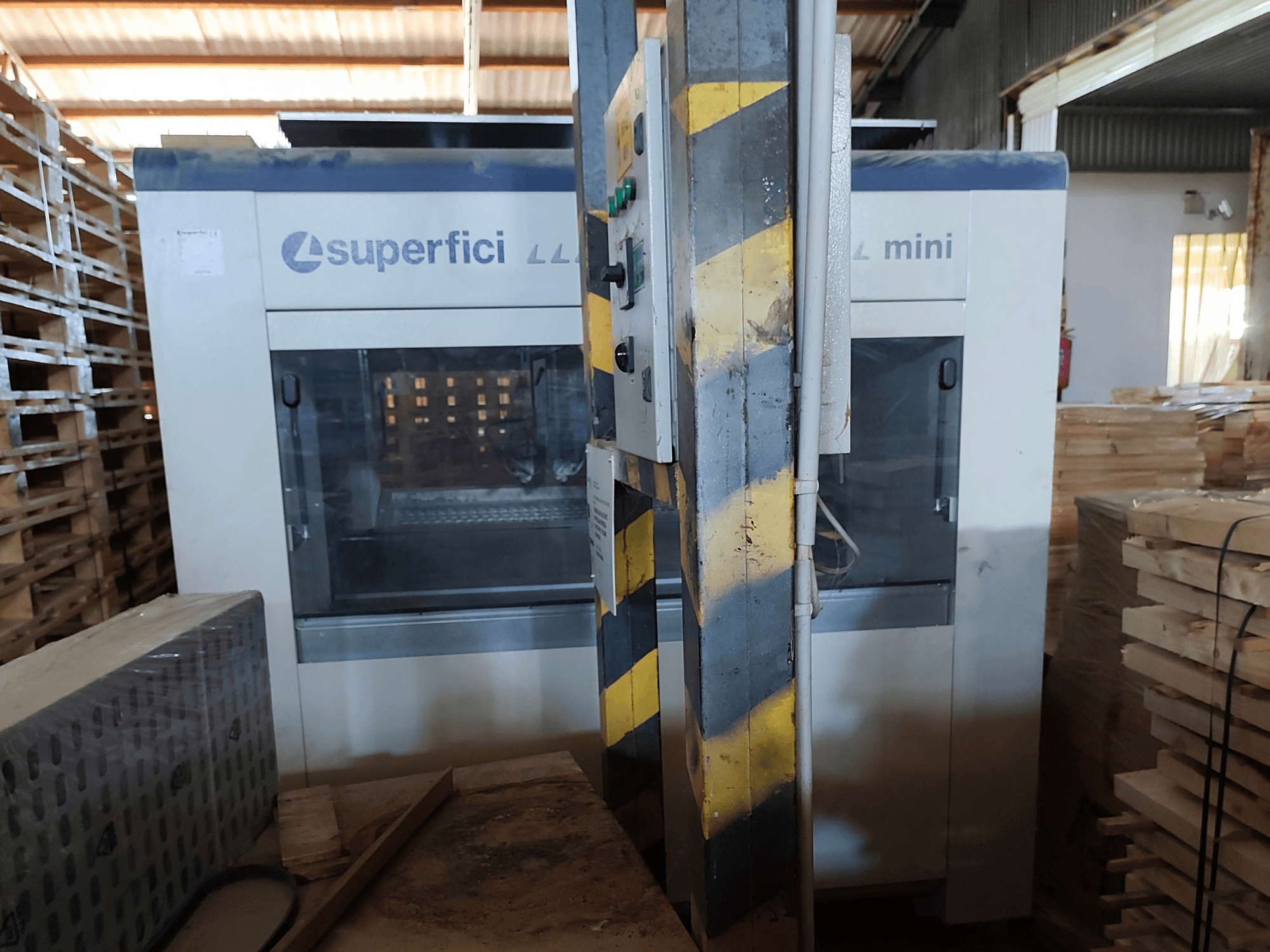 SCM Superfici Mini – träbearbetningsmaskin sedd framifrån, med kontrollpanelen och de omgivande träpallarna.