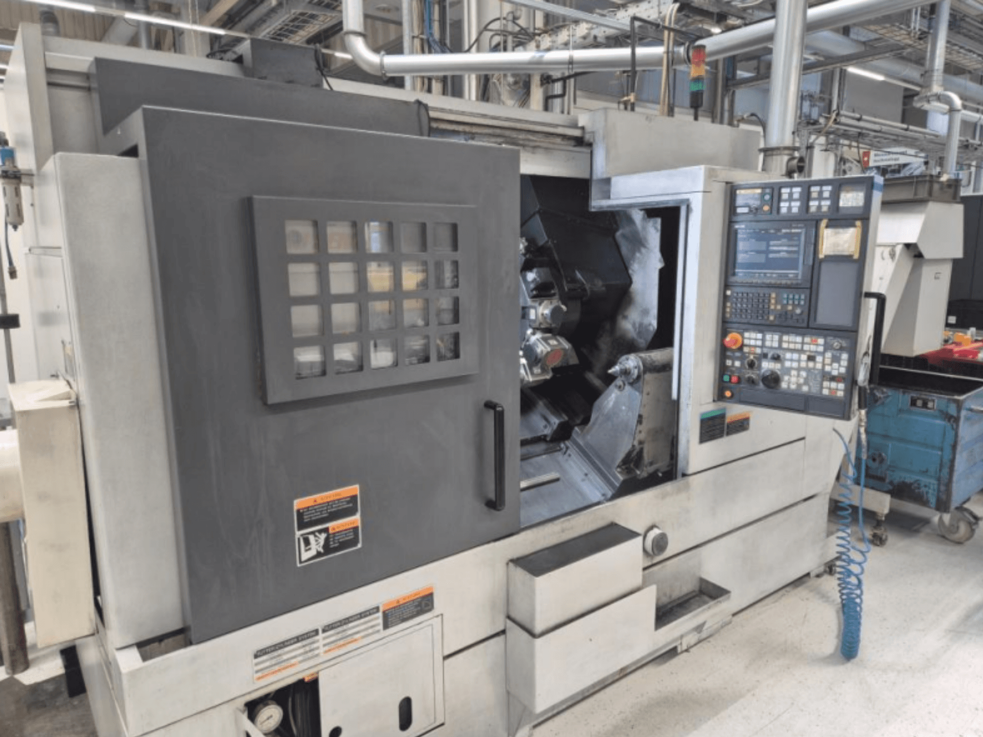 CNC-svarv med kontrollpanel, vy framifrån. Med synligt arbetsområde och säkerhetsfönster, okänt varumärke.