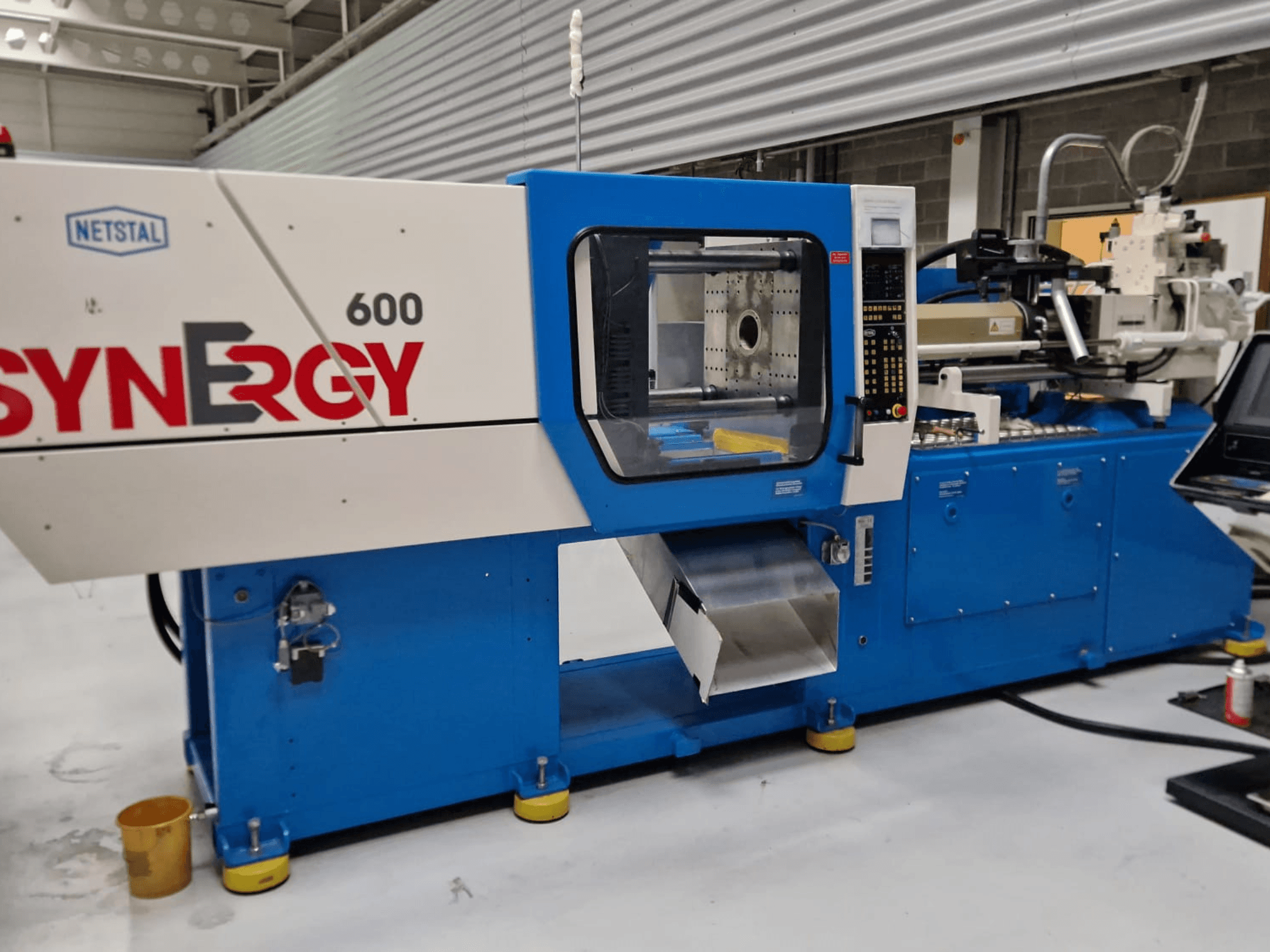 Netstal Synergy 600-230 hydraulisk formsprutningsmaskin, sidovy som visar kontrollpanelen och formsprutningsområdet.