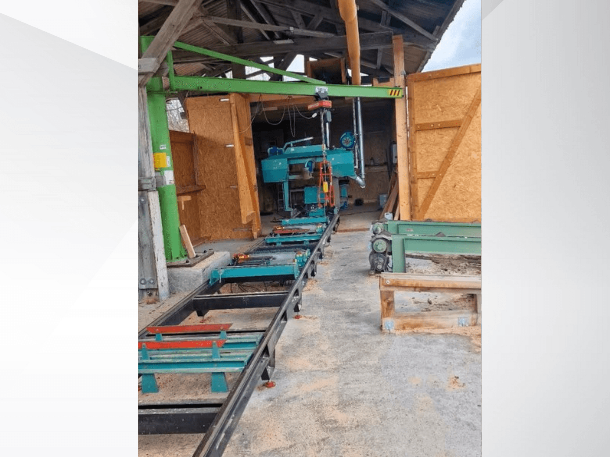 Horisontell bandsågsmaskin i verkstad, sedd framifrån. Utrustningen inkluderar ett spår och ytterligare gröna tillbehör.