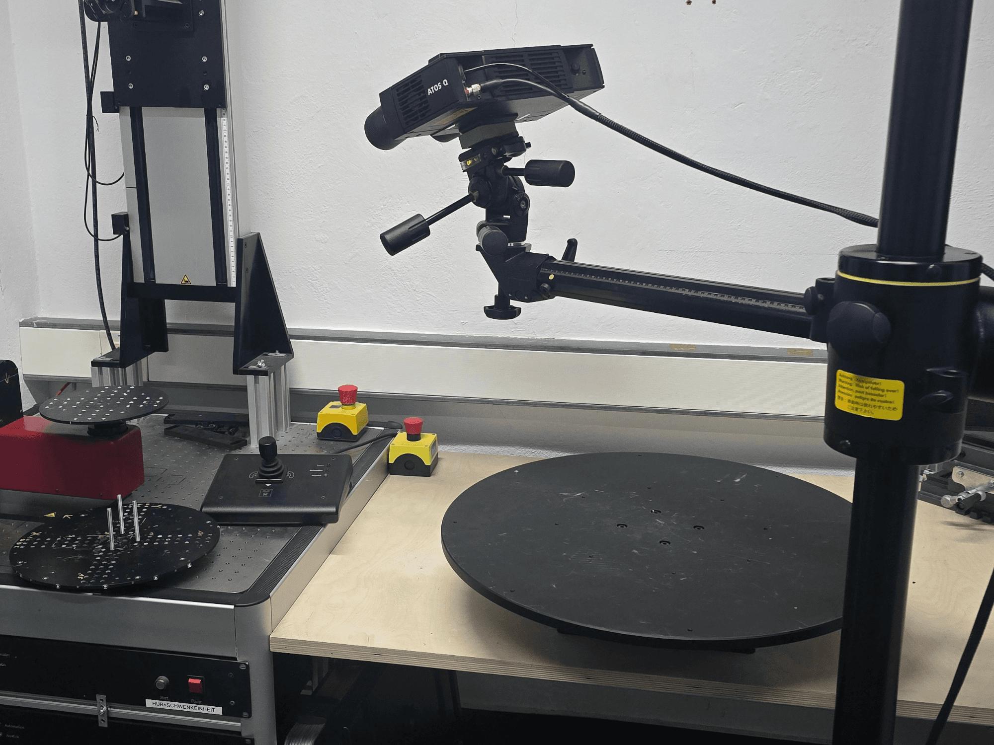 Framifrånvy av den optiska mätmaskinen ZEISS ATOS Q 12M, med ett skanningshuvud, en kontrollpanel och en roterande cirkulär plattform.