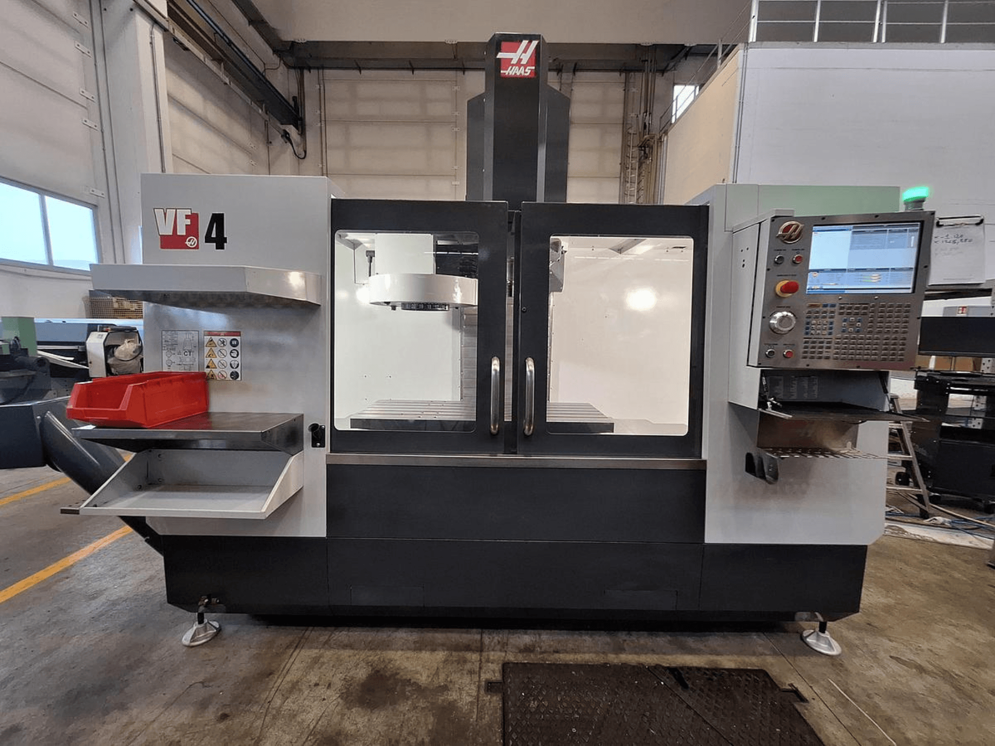 Haas VF-4 vertikala bearbetningscenter, framifrån, med kontrollpanel, verktygshållare och rymligt arbetsområde.