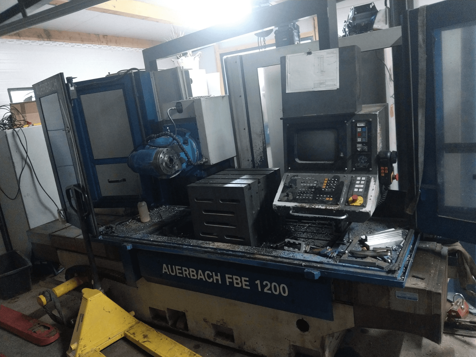 Auerbach FBE 1200 metallborrmaskin, vy framifrån, med kontrollpanel, motor och metallspån på arbetsytan.