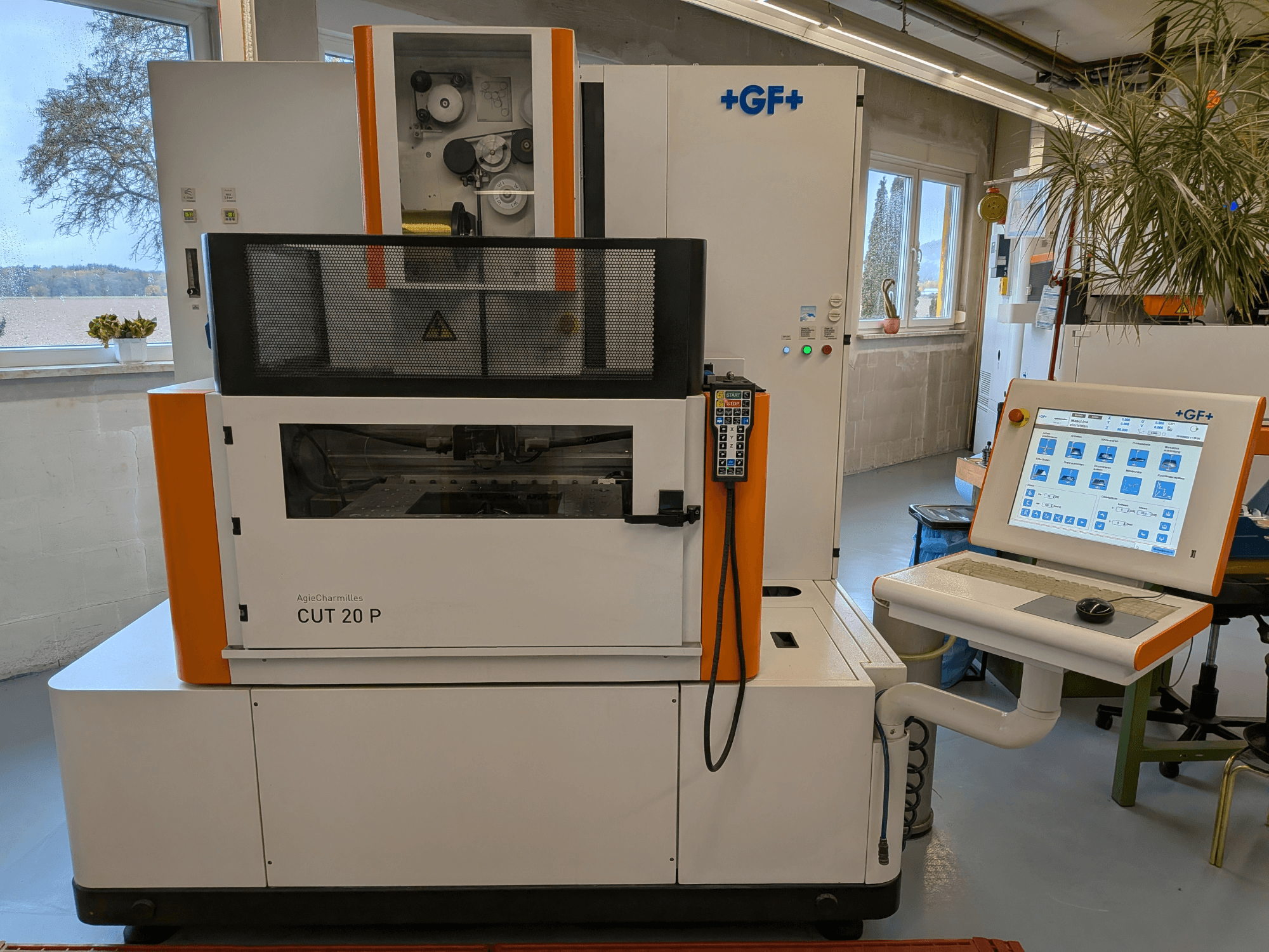 En AgieCharmilles Cut-20 P-trådgnistmaskin sedd framifrån med kontrollpanel och display, placerad i en väl upplyst verkstad.