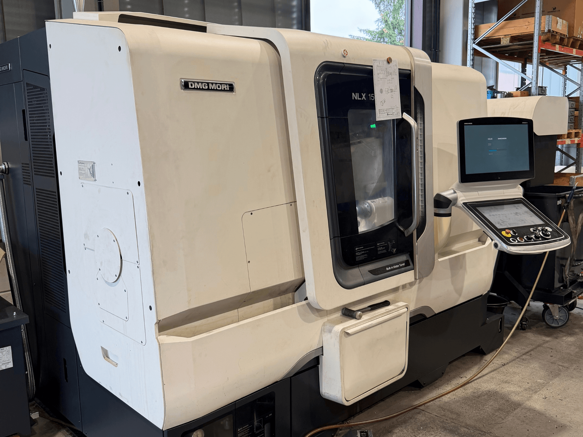 Framifrånvy av DMG MORI NLX1500MC/500 horisontell svarv, där kontrollpanelen och spindeldelen syns genom det genomskinliga locket.