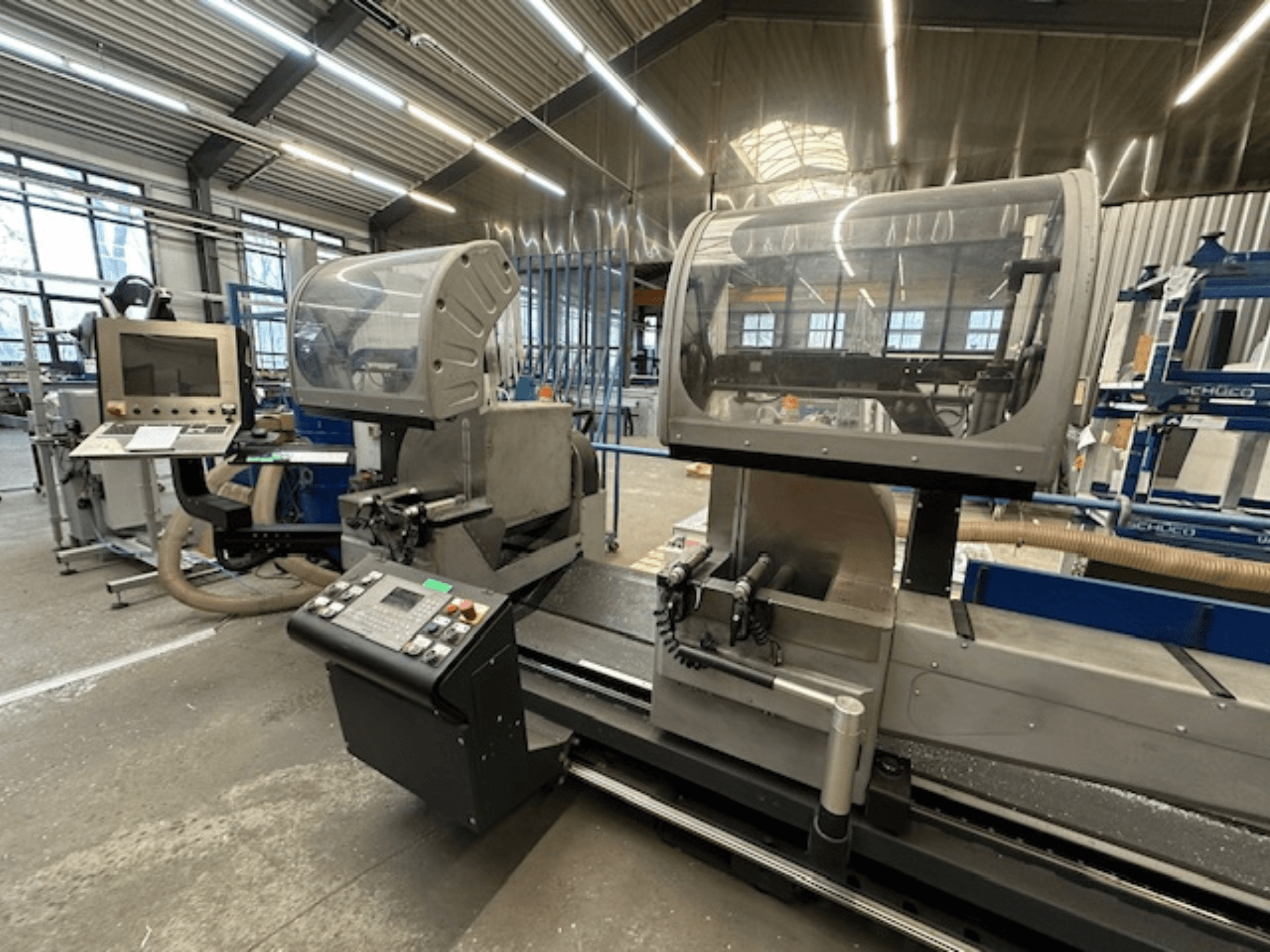 SCHÜCO PDG E CUT metallcirkelsåg, framifrån, med kontrollpanel, skyddskåpor och kapområde i en verkstadsmiljö.