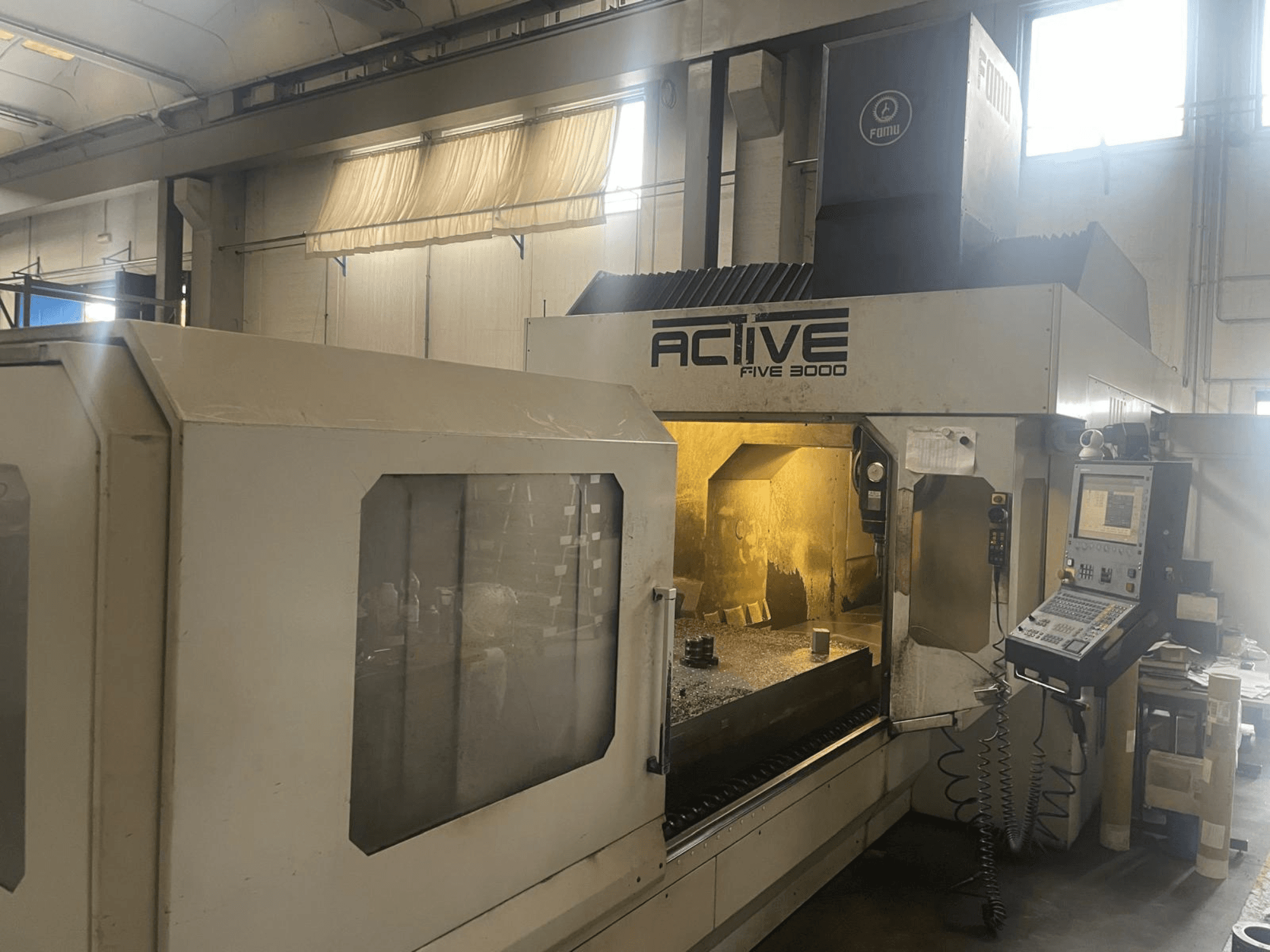 Frontvy av CNC-maskinen ACTIVE Five 3000, som visar kontrollpanelen och arbetsområdet med en delvis bearbetad detalj inuti.