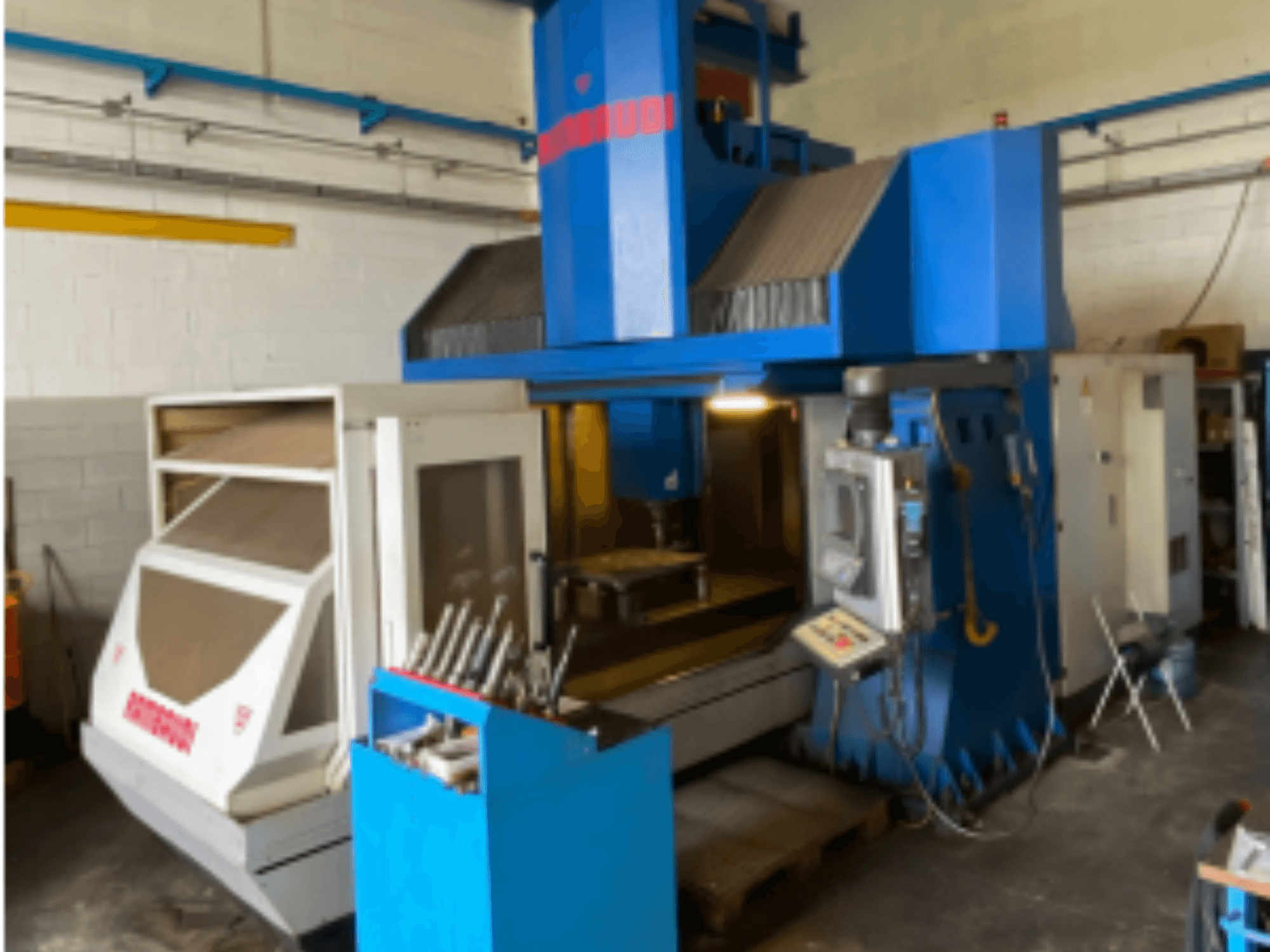 Vertikal fleroperationsmaskin Rambaudi RF103, framifrån visar reglage, verktygsförvaring och bearbetningsområde. Blå och vit exteriör.