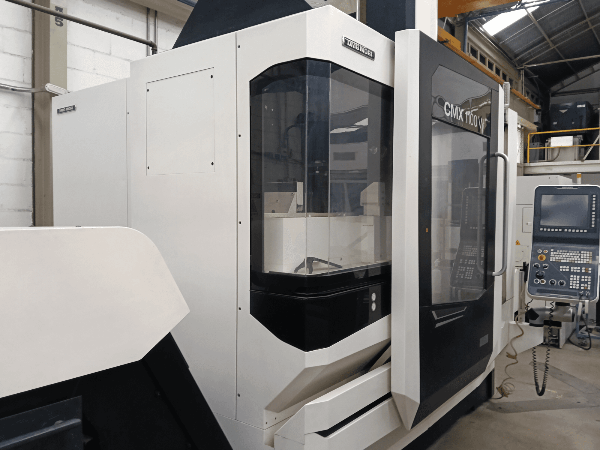 DMG MORI MORI CMX 1100 V vertikalt bearbetningscenter, framifrån, med kontrollpanelen och glaskåpan i förgrunden.