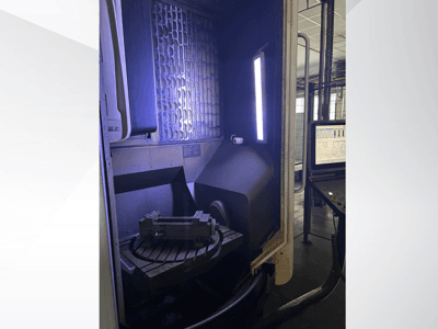 DMG MORI DMU 65 MonoBlock vertikalt bearbetningscenter, framifrån sett med roterande bord med arbetsstycke och manöverpanel.