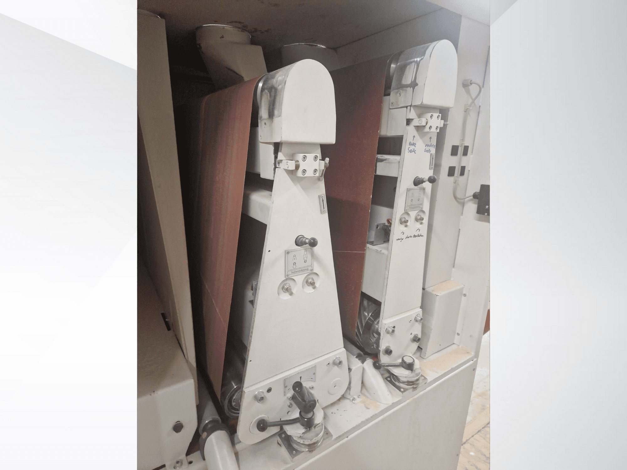 Två industriella slipmaskiner med röda slipband, framifrån, visar reglage och metallkomponenter.