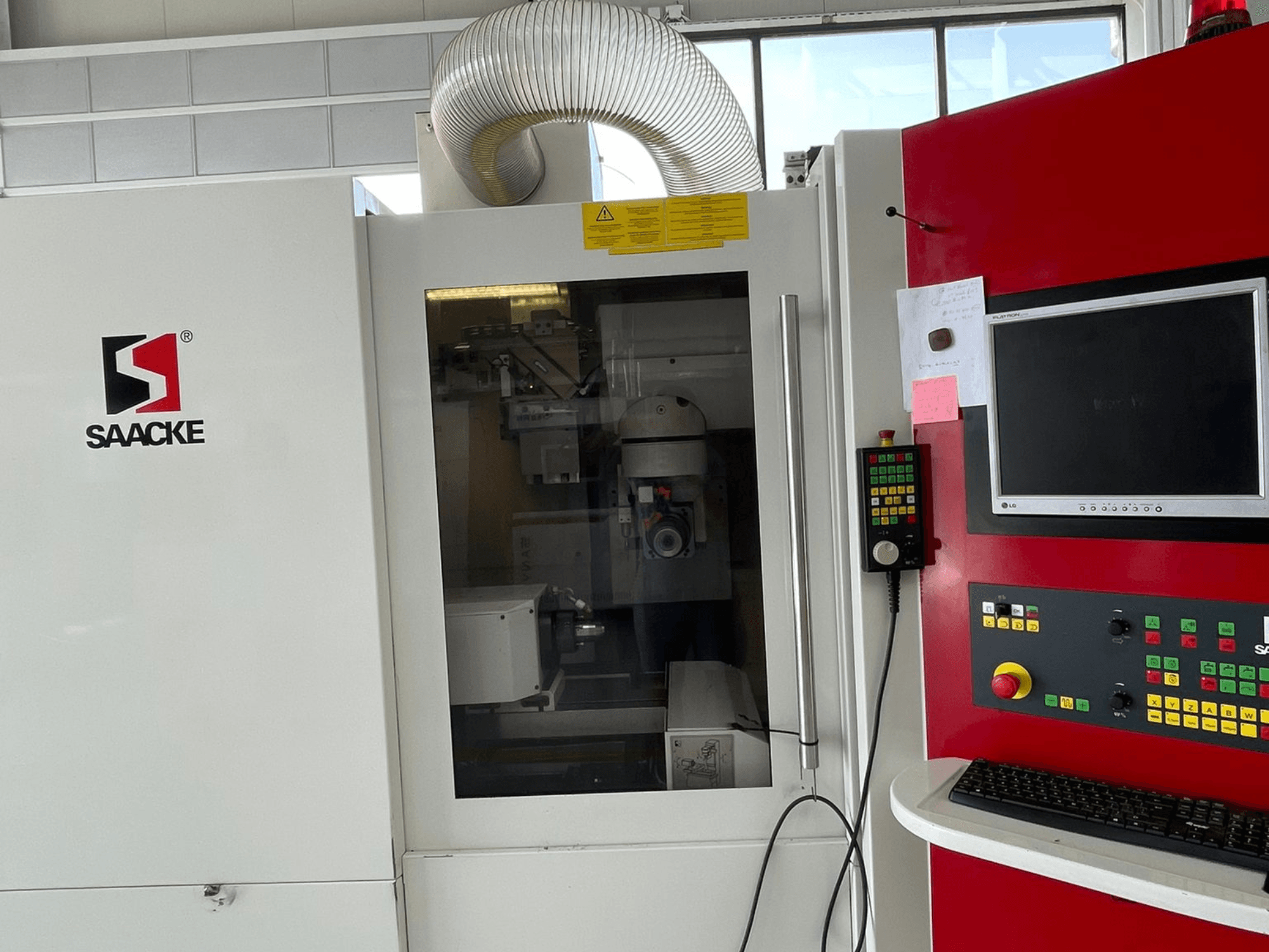 SAACKE-maskin i vitt och rött, framifrån, med kontrollpanel, monitor och synliga inre delar genom glas.