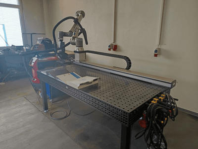 FRONIUS TransSteel 4000 pulssvetscell sedd från sidan, med robotarm, arbetsutrymme och strömanslutningar.