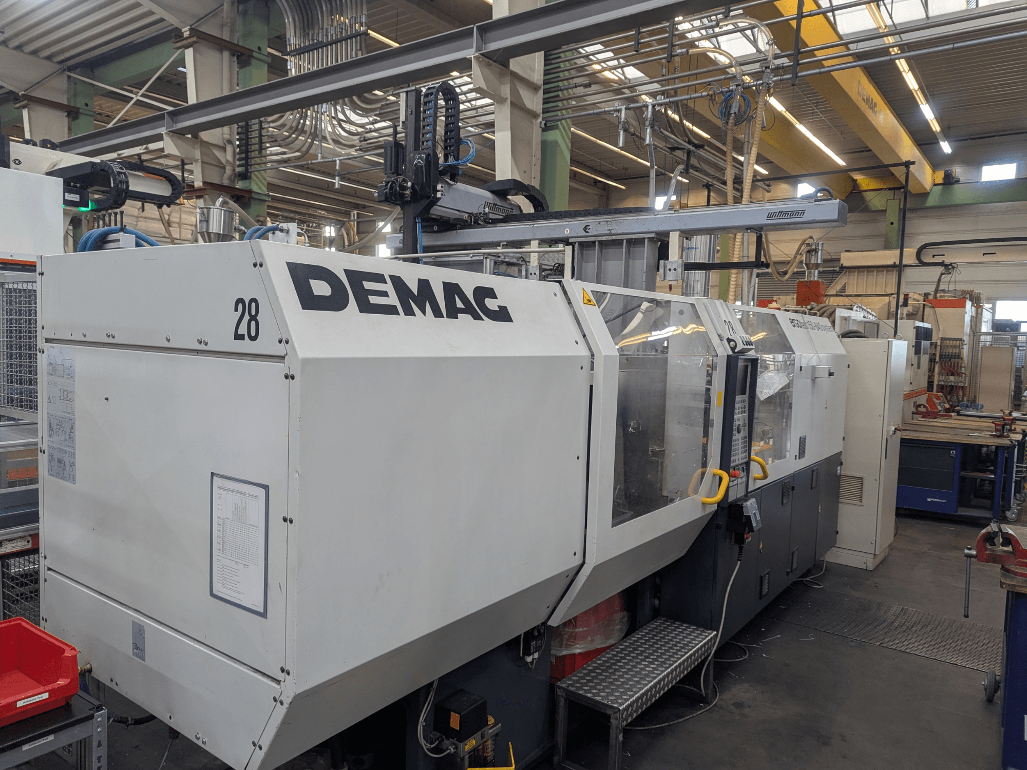 Frontvy av en DEMAG ERGOTECH 1500-840 hydraulisk formsprutningsmaskin, som visar driftskontroller och säkerhetsfunktioner.