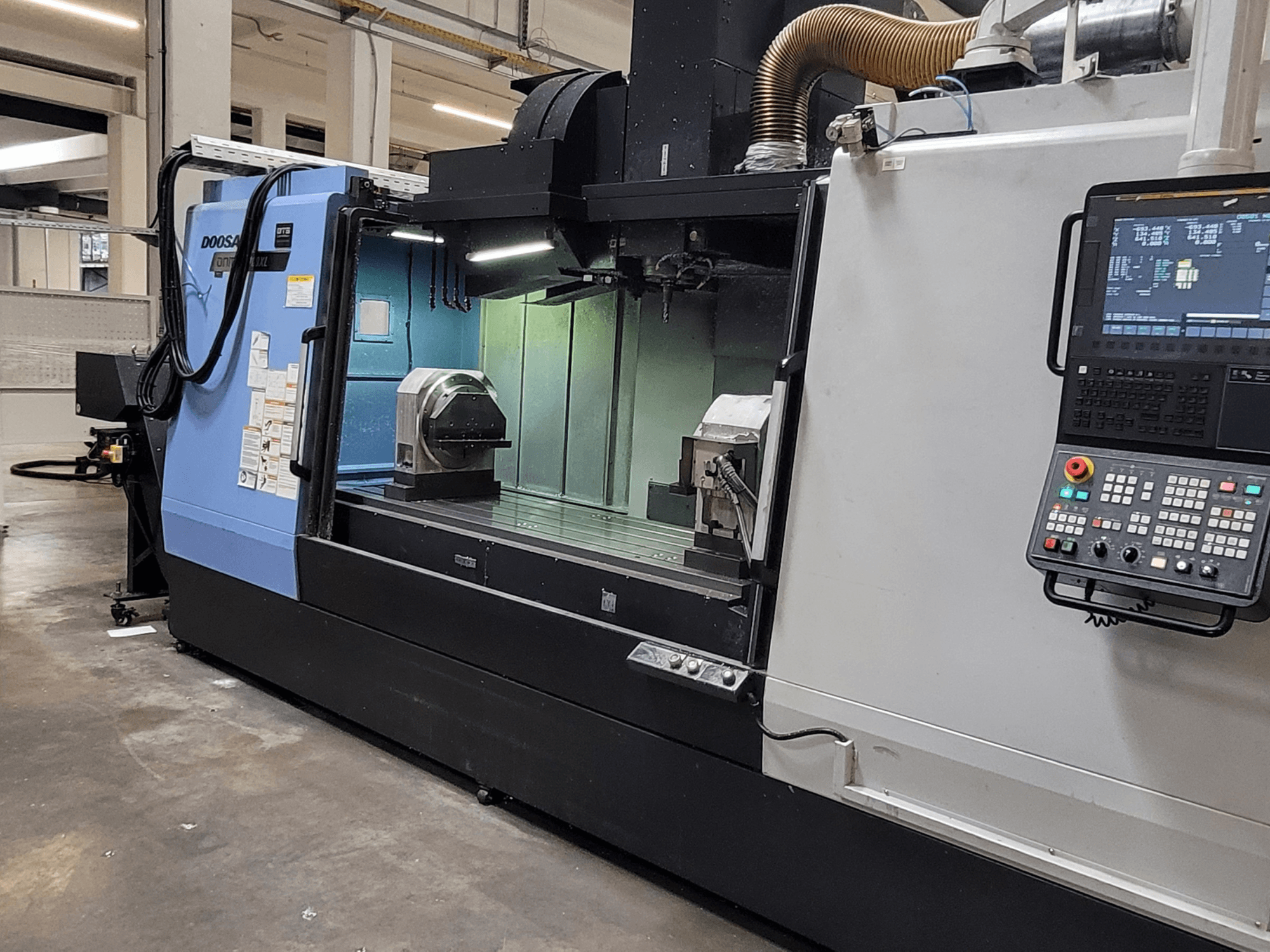 DOOSAN DNM 6700 XL vertikalt bearbetningscenter, framifrån sett med kontrollpanel, arbetsbord och bearbetningsområde.