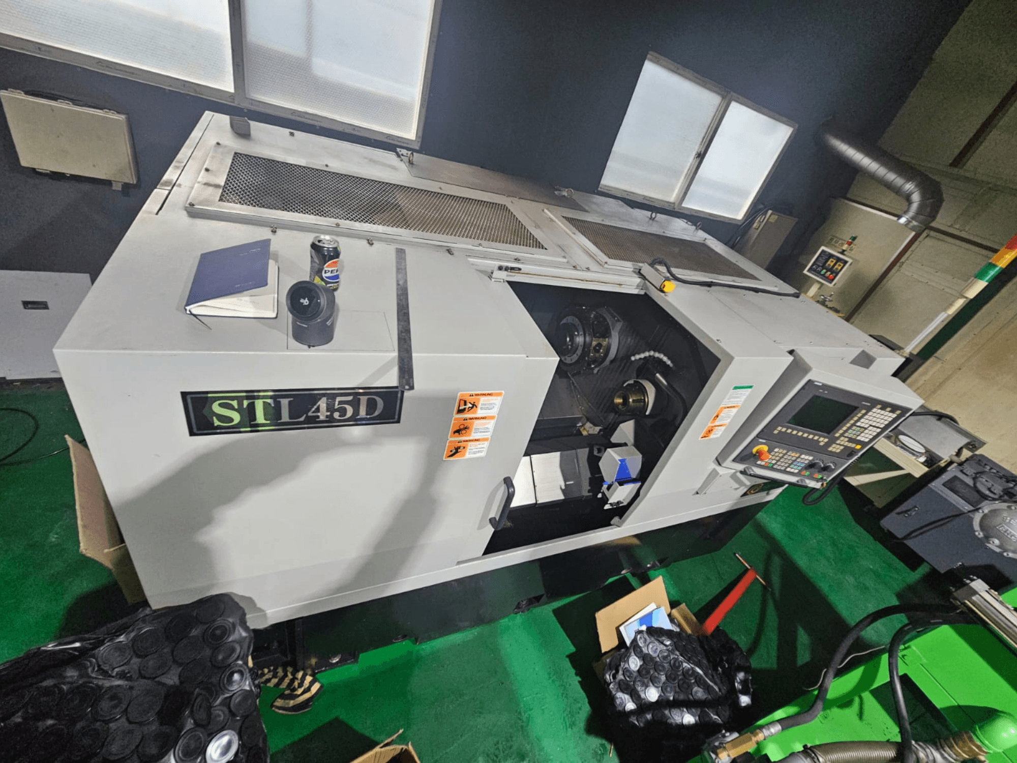 STL45D CNC-maskin sedd ovanifrån, med kontrollpanel, cylindrisk del, bärbar dator och burk ovanpå.