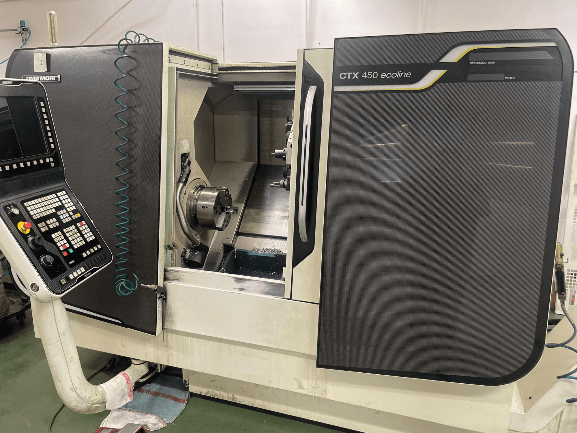 DMG MORI CTX 450 ecoline CNC-maskin i sidovy, visar kontrollpanel, chuck och bearbetningsområde.