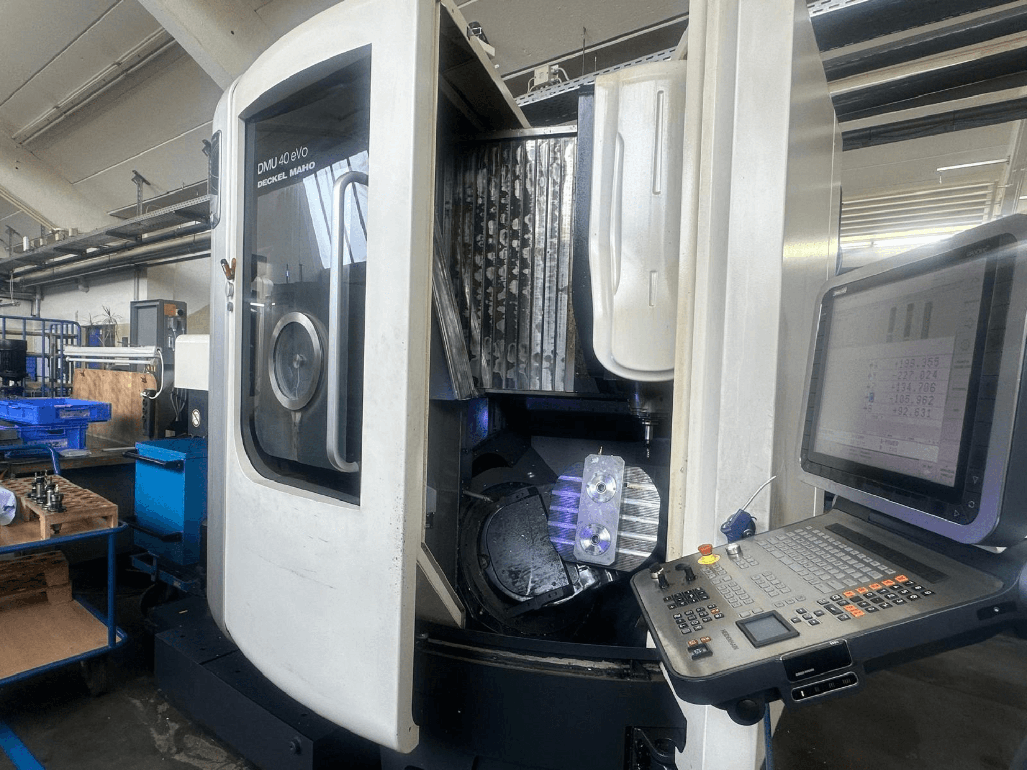 DMU 40 eVo fräsmaskin från Deckel Maho i en verkstad, framifrån med kontrollpanel och metallstycke i spindeln.