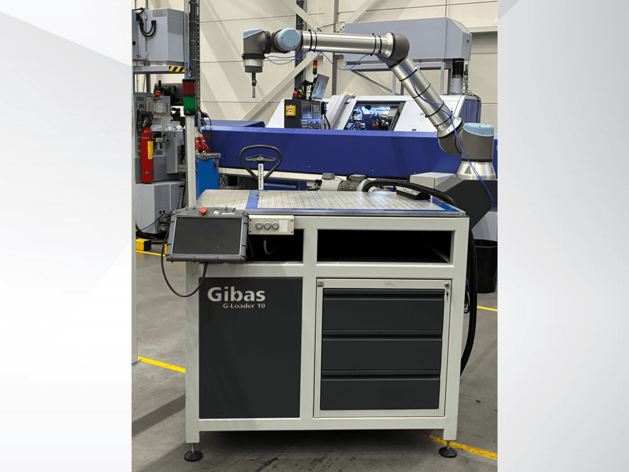 Gibas G-Loader 10 med robotarm, vy framifrån; har pekskärmskontroll och lådförvaring i industriell miljö.