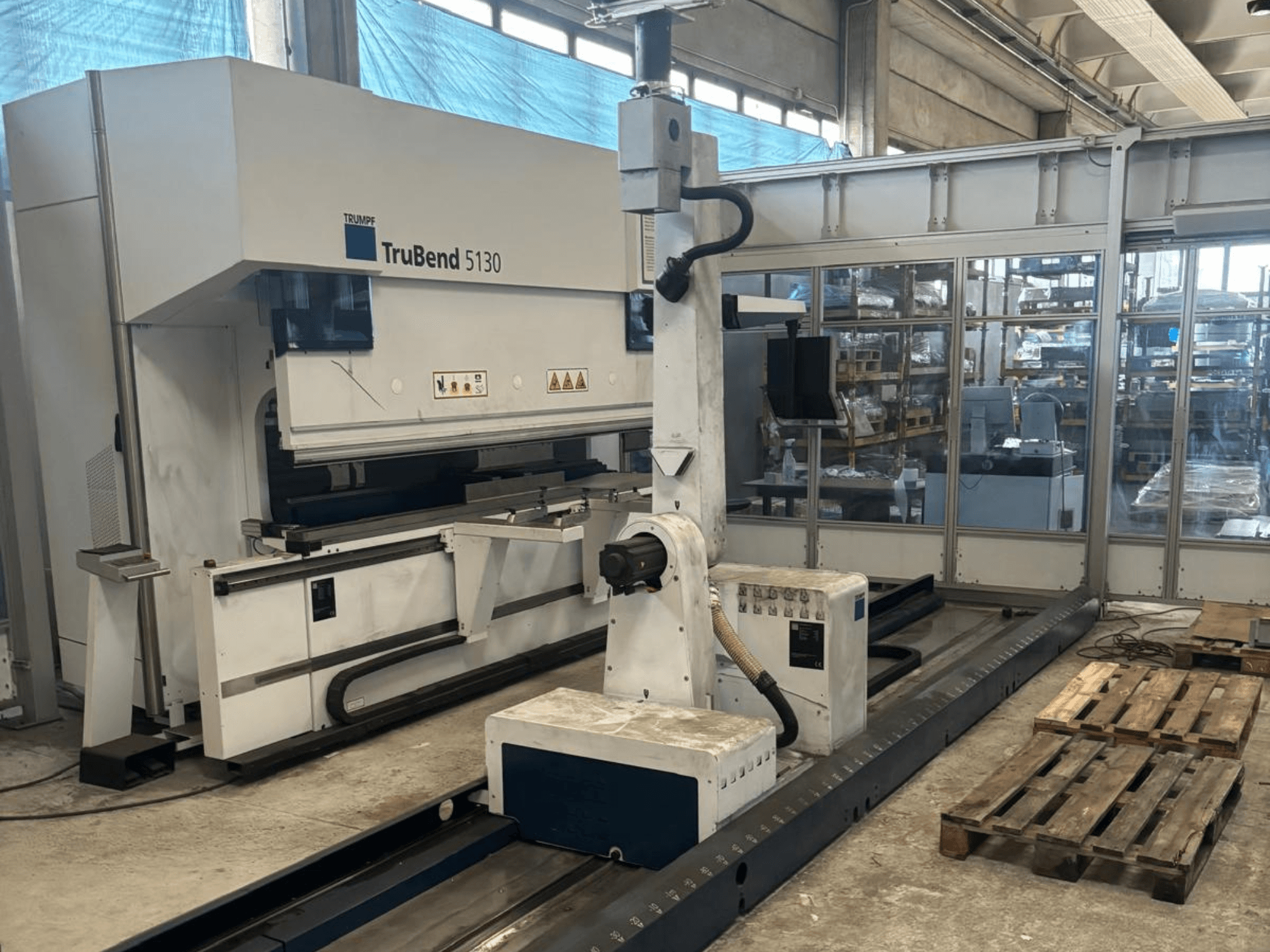 TruBend 5130 bockningsmaskin från Trumpf, framifrån, med kontrollpanel och pallar i en fabriksmiljö.