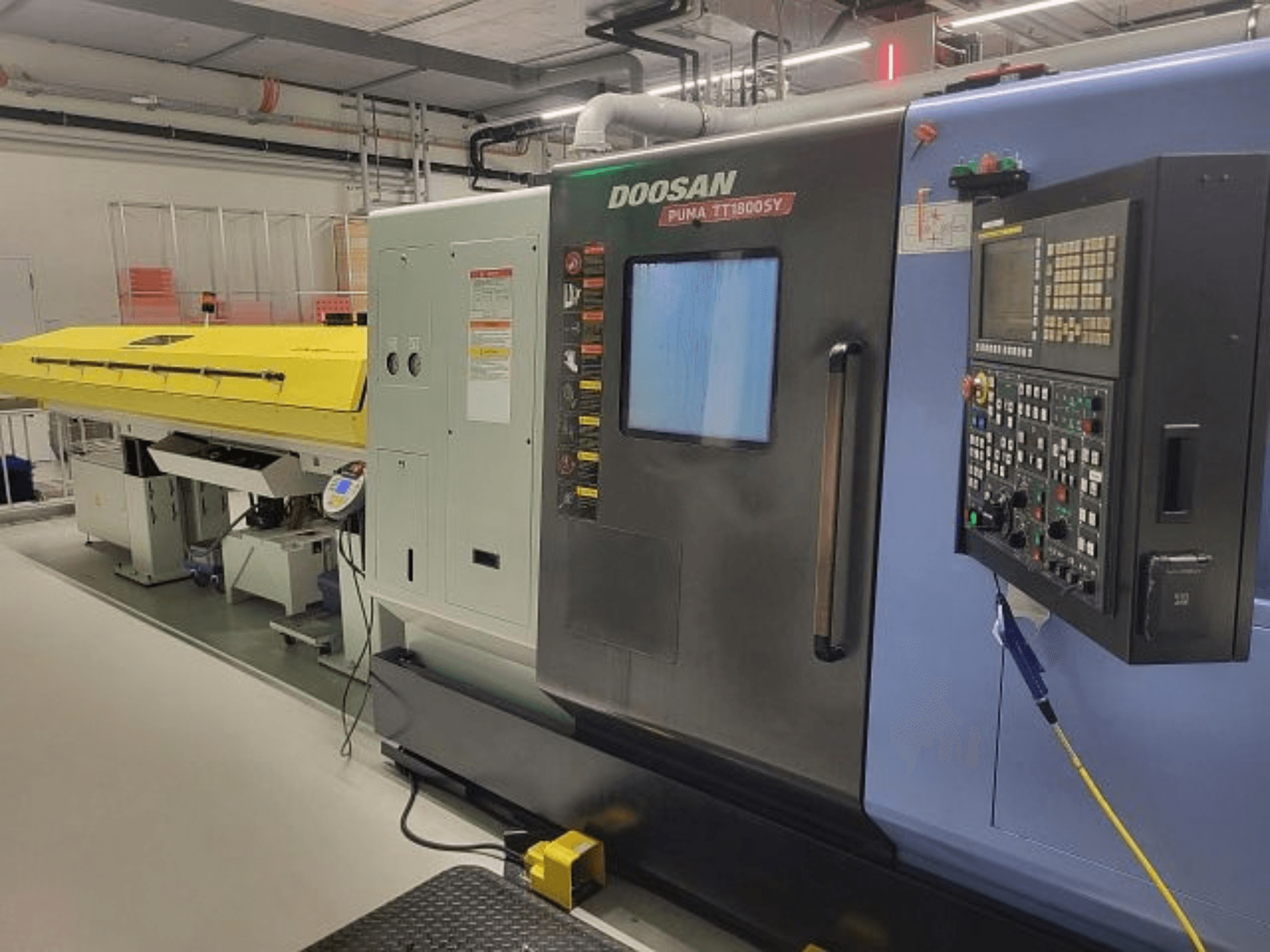 DOOSAN PUMA TT 1800 SY svarv- och fräsmaskin, framifrån sett med kontrollpanel och gult skydd, i industriell miljö.