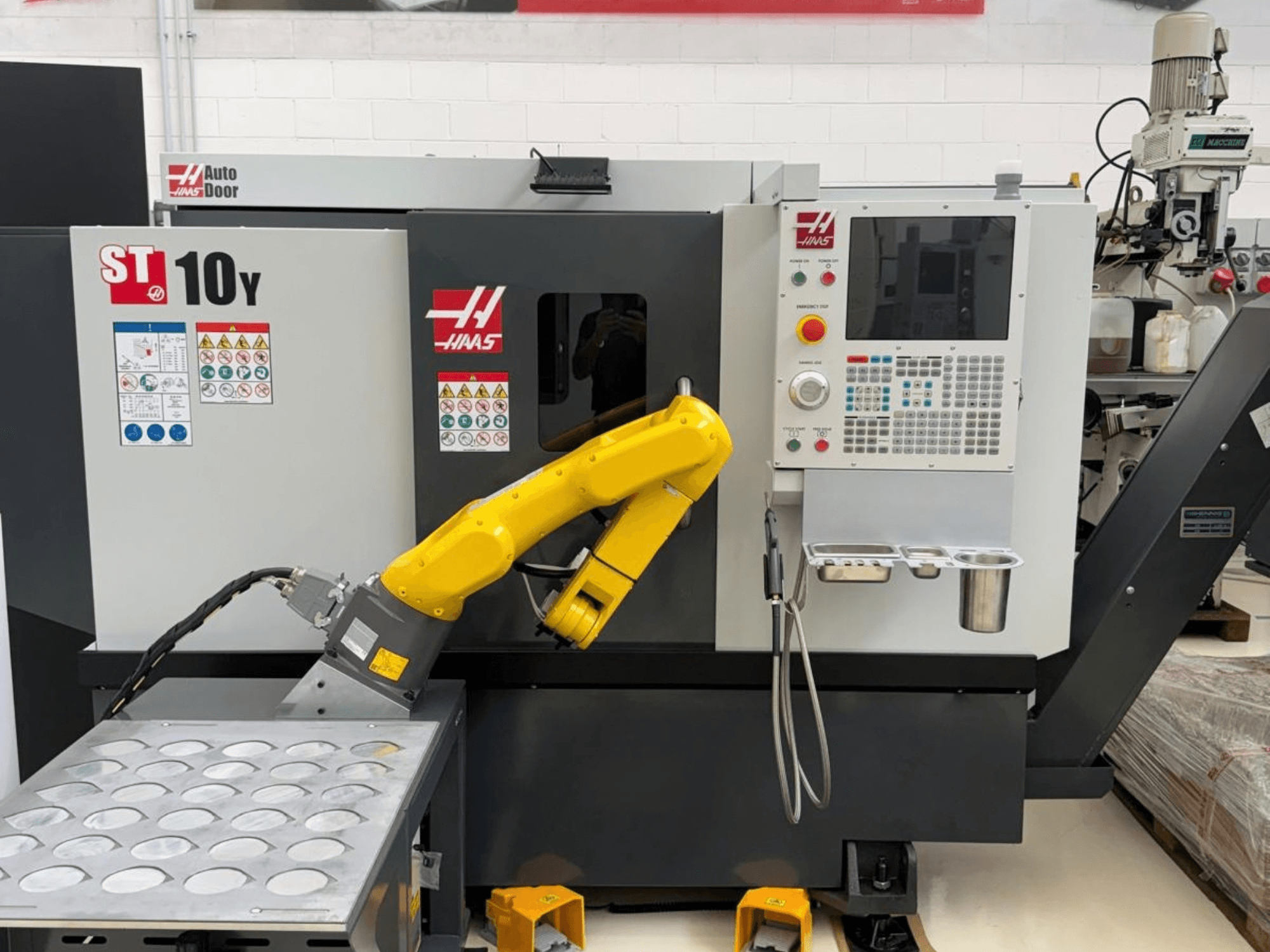 En Haas ST-10Y horisontell svarv sedd framifrån, utrustad med en robotarm och en kontrollpanel med verktygshållare.