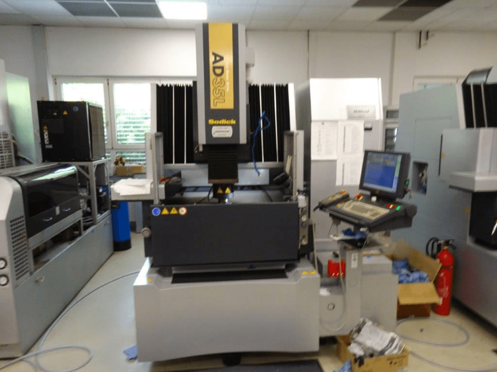 Sodick AD35L CNC-maskin framifrån, med kontrollpanel, kylenhet och säkerhetsindikatorer.