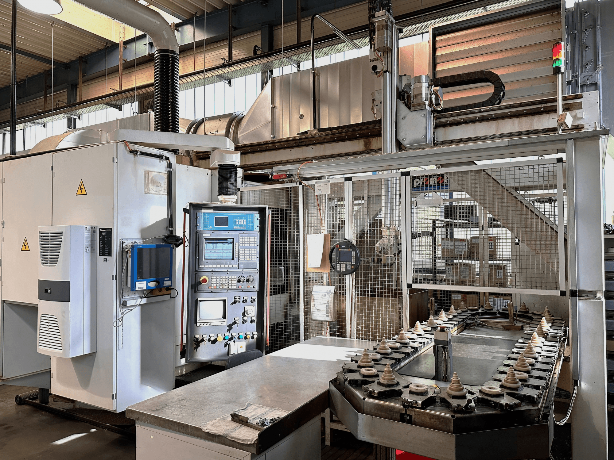 Industrimaskin med kontrollpanel, kylaggregat och transportör. Vy framifrån med starka lampor och säkerhetsskyltar.