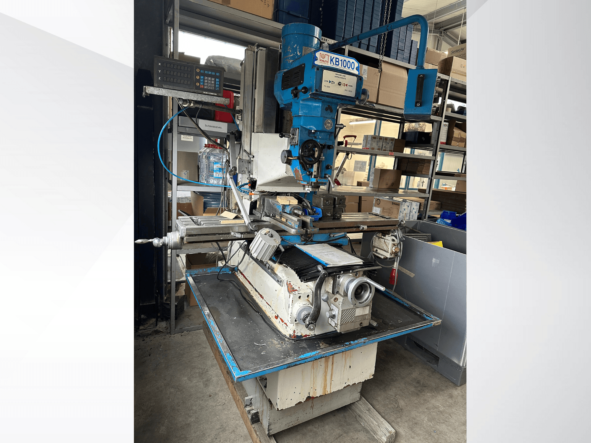 Vertikal fräsmaskin KB1000 med digital display, sidovy som visar bordet, spindeln och verktygshållaren.