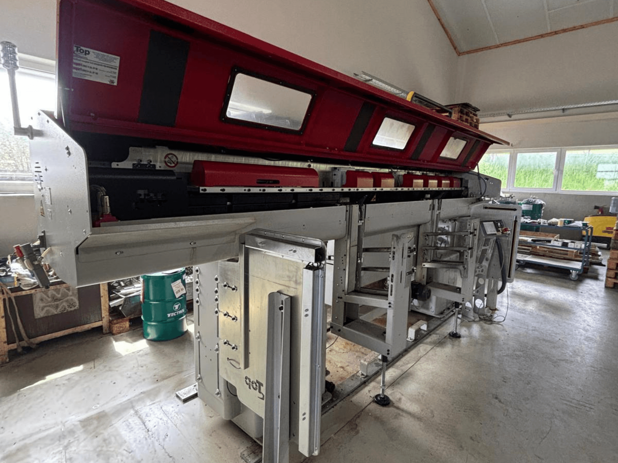 TOP Automazioni Top Loader ETL 10-75 sett från sidan, med en röd övre del och komplexa maskinkomponenter.