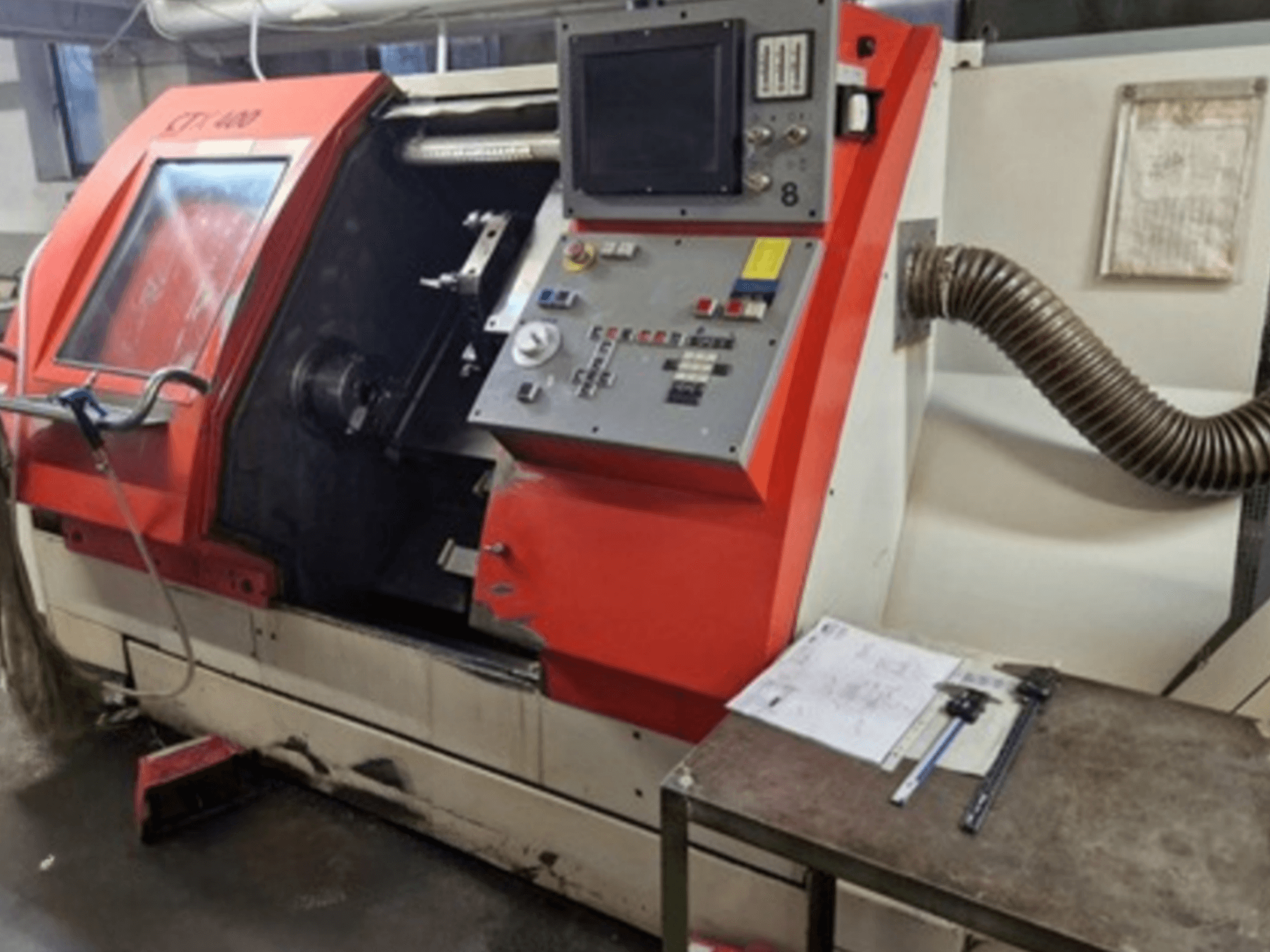 Gildemeister CTX 400 horisontell svarv, framifrån med kontrollpanel och avgasslang. Inklusive mätverktyg på bordet.