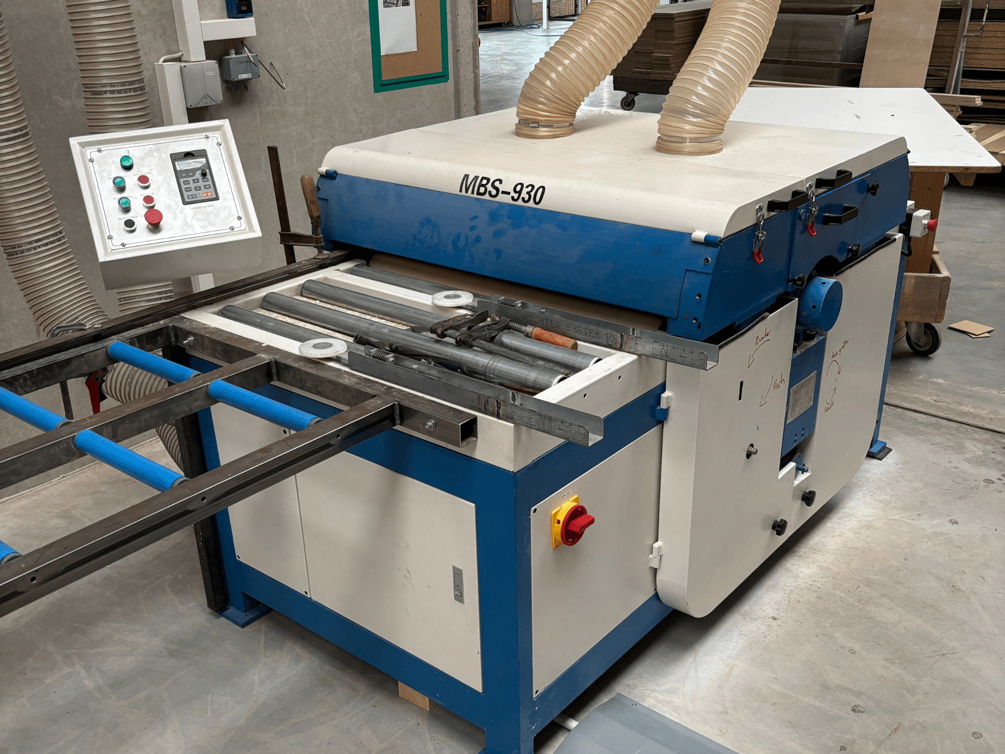 Träbearbetningsmaskin MBS-930 med kontrollpanel och valsar, sedd från sidan, med slangar för dammutsug.