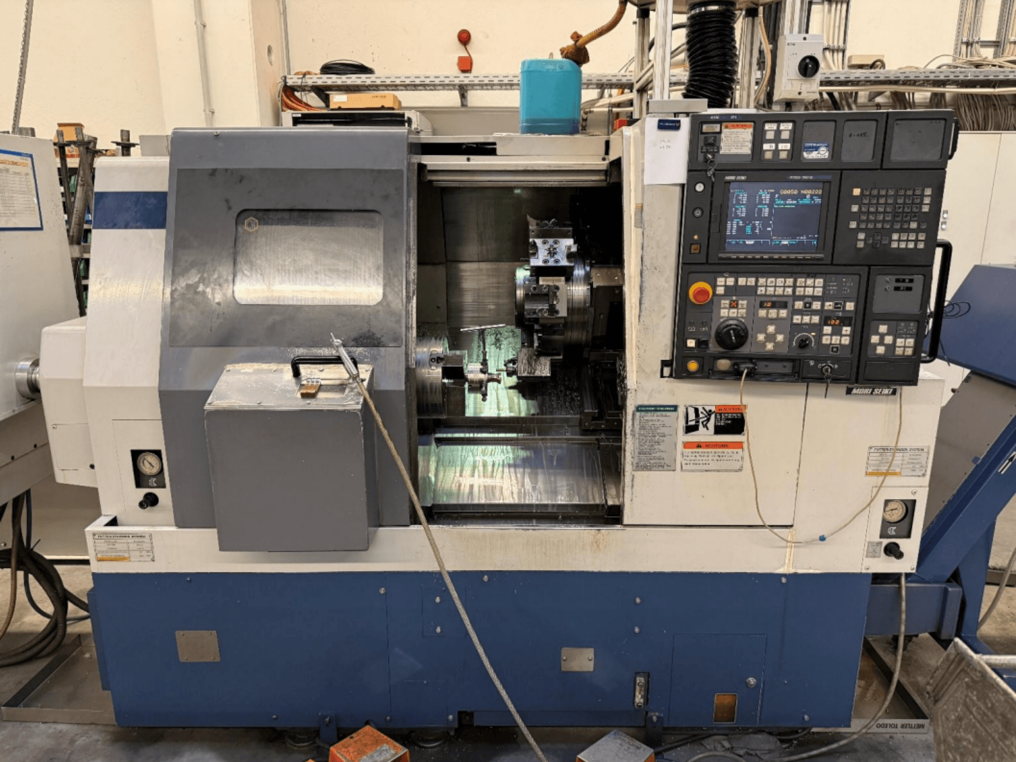 MORI SEIKI SL-250ASMC svarv- och fräscenter, framifrån med kontrollpanelen och arbetsstyckeschucken i drift.