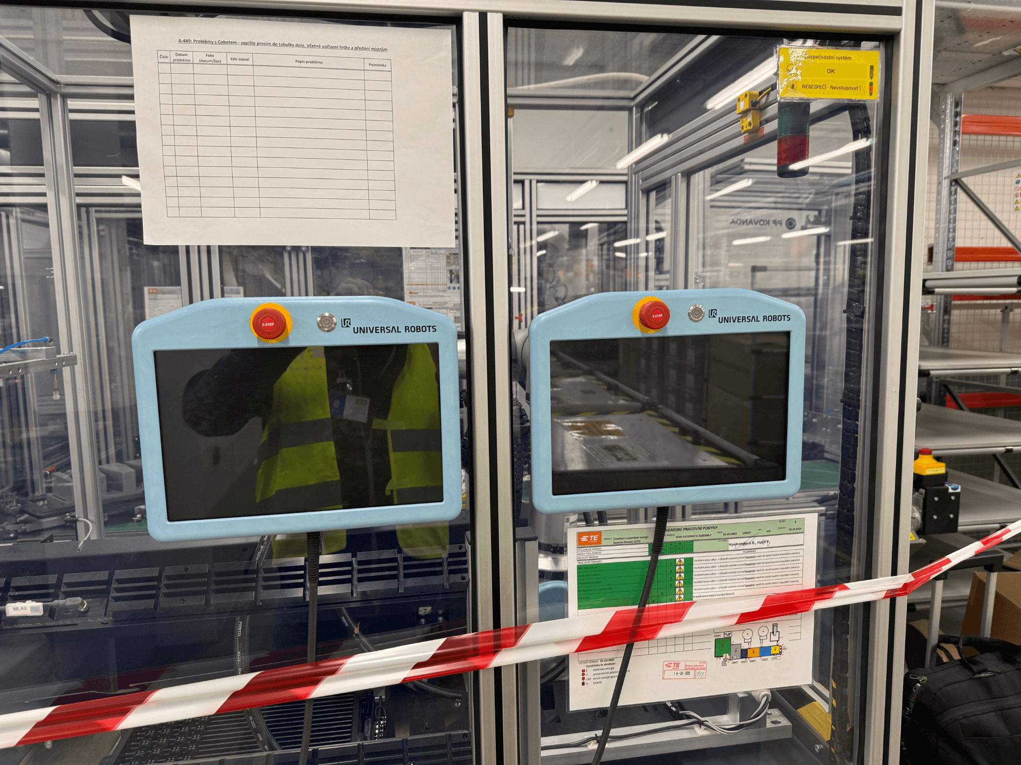 Kontrollpanel för Universal Robots UR5 e robotarm, med två bildskärmar, nödstoppsknappar och säkerhetsinstruktioner.