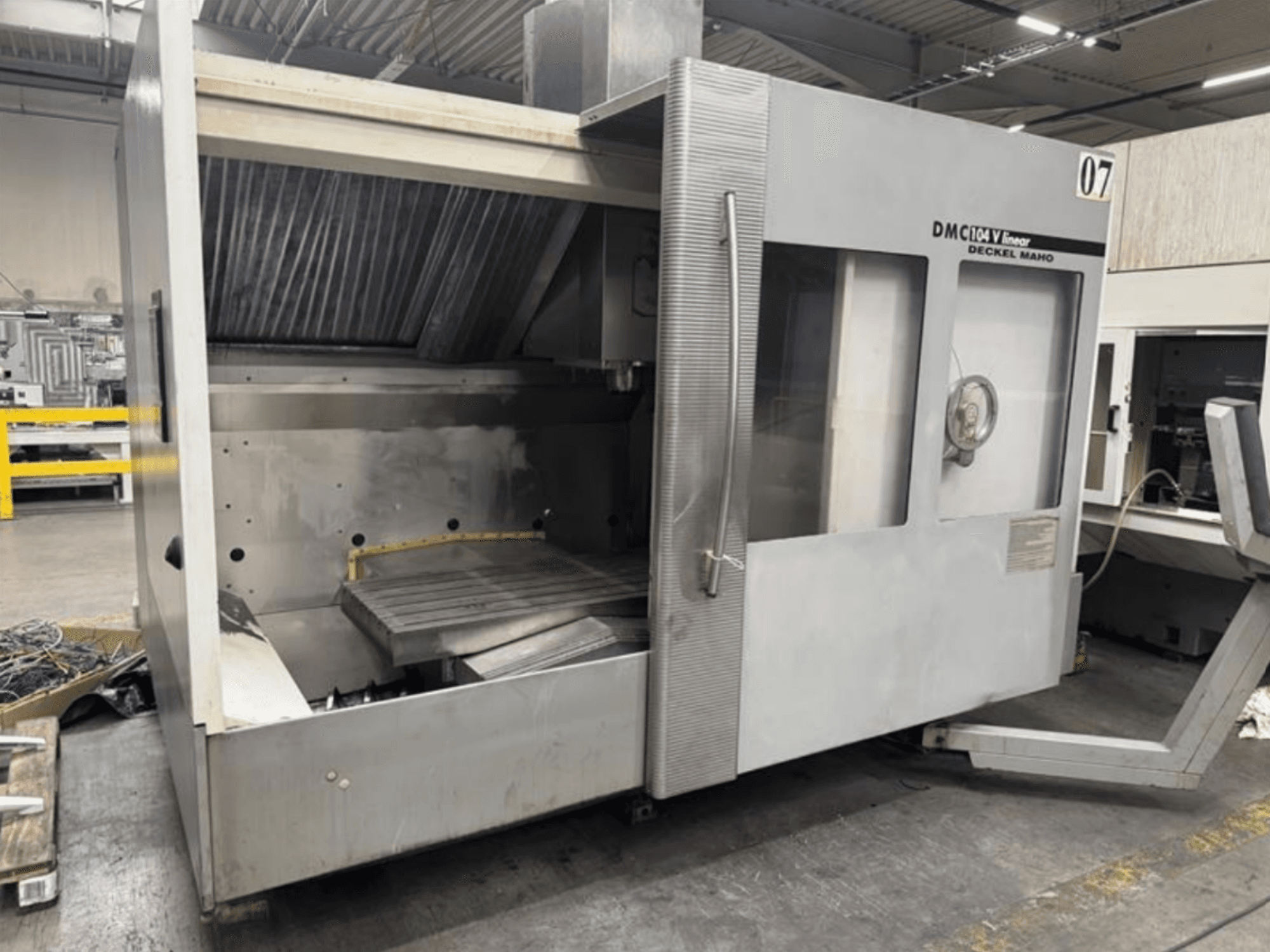 Linjärmaskin DMC 104 V från Deckel Maho, vy framifrån, med ett tomt bearbetningsområde med ett stort arbetsbord.