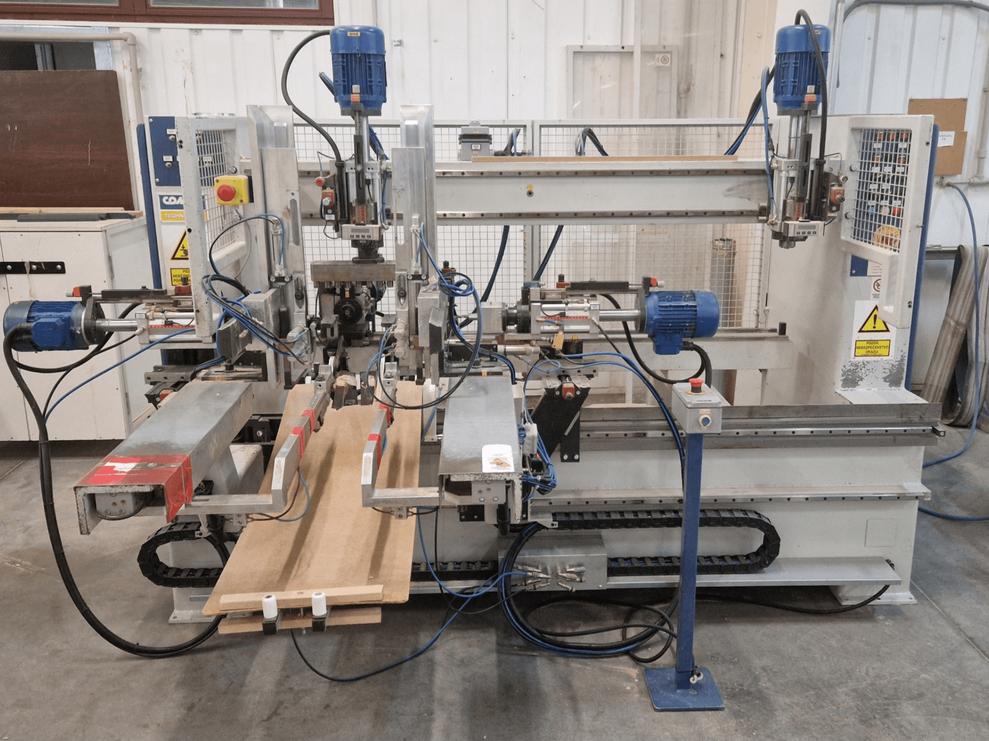 COMEC FMOV 1500 flerspindlig borrmaskin framifrån, visar dubbla spindlar, kontrollpanel och trästycke i drift.