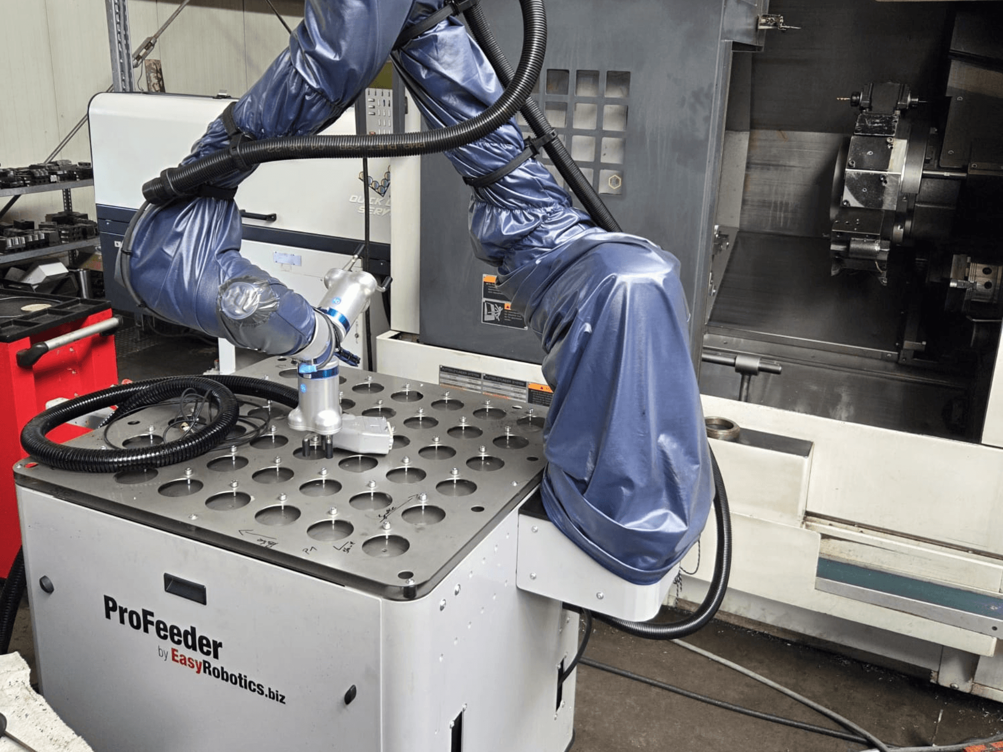 Samverkande robot EASYROBOTICS ProFeeder framifrån, med en robotarm placerad över ett bord av perforerad metall.