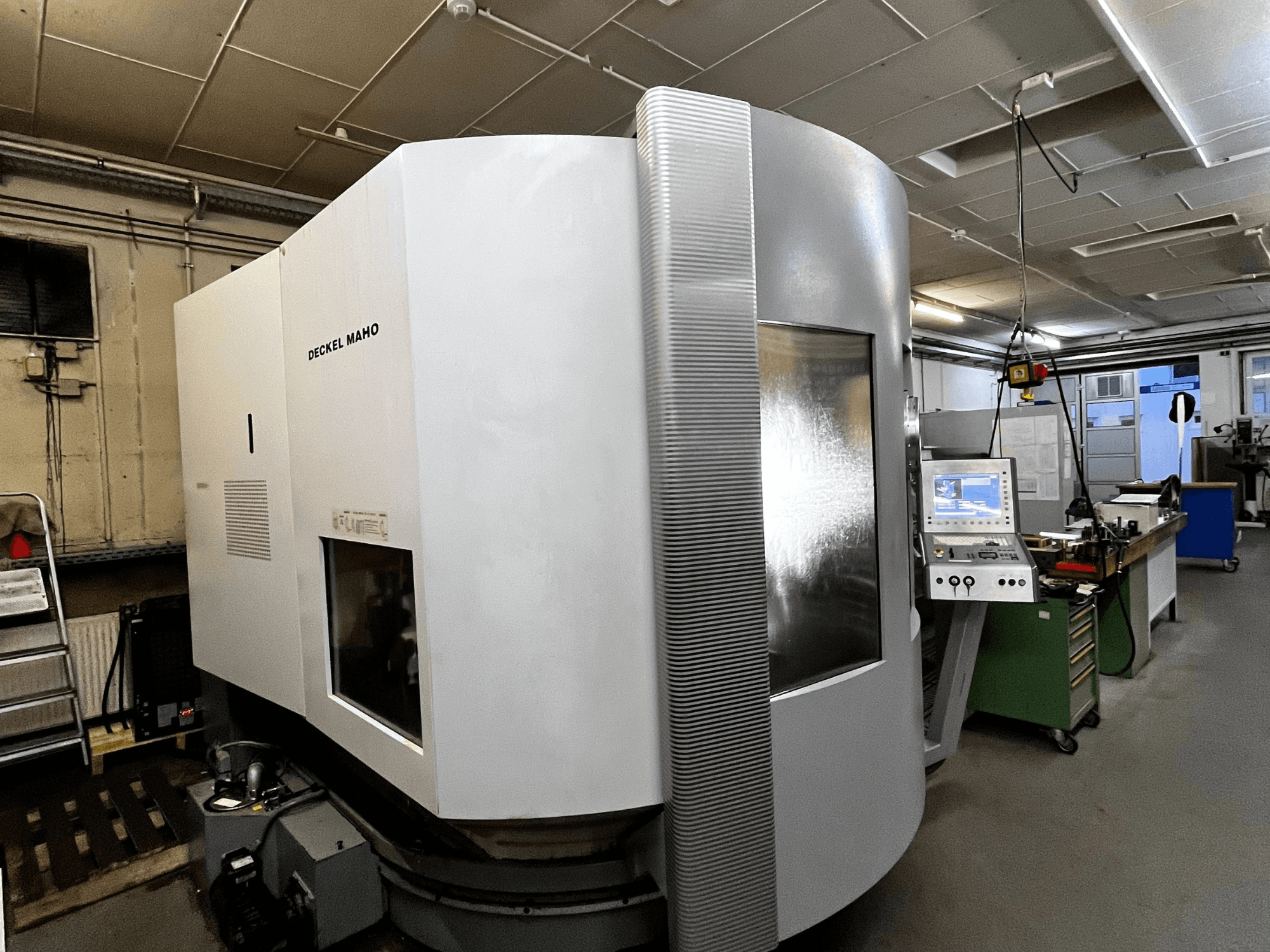 Deckel Maho CNC-maskin, framifrån, vit exteriör, kontrollpanel synlig, verkstadsmiljö.