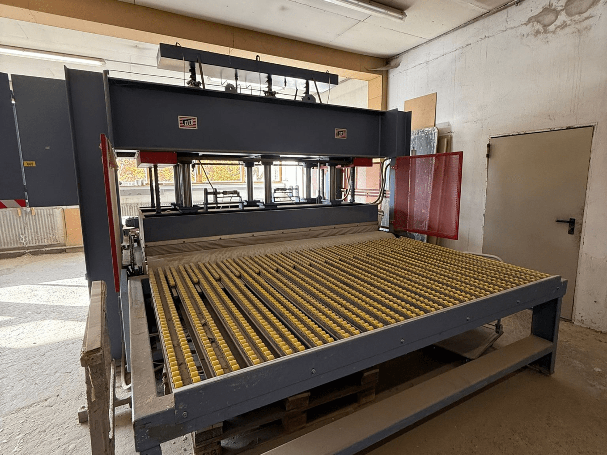 Industrimaskin med gula valsar, framifrån, märkeslogotyp synlig, används för bearbetning av material i en verkstadsmiljö.