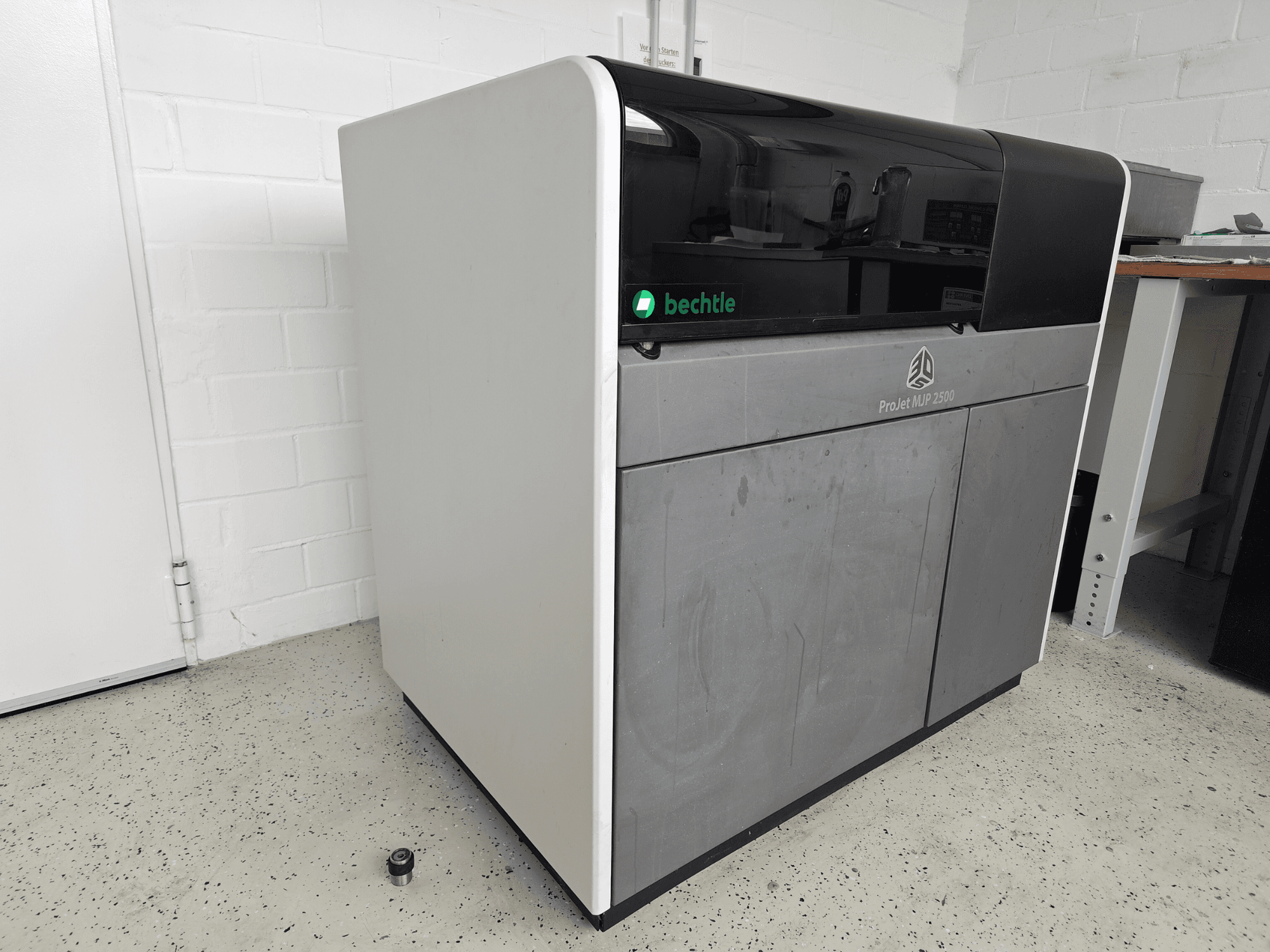 3D Systems ProJet MJP 2500 Plus-plastskrivare sett framifrån; har en elegant design med en mörk ovansida och en ljus kropp.