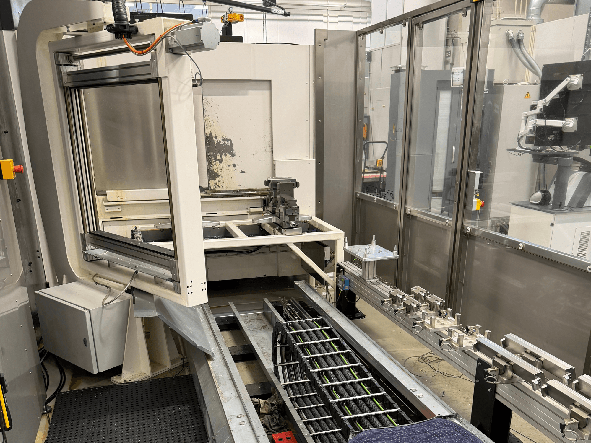 Automatiserad industriell arbetsstation som visar en robotarm, ett skensystem och en kontrollpanel i sidovy.