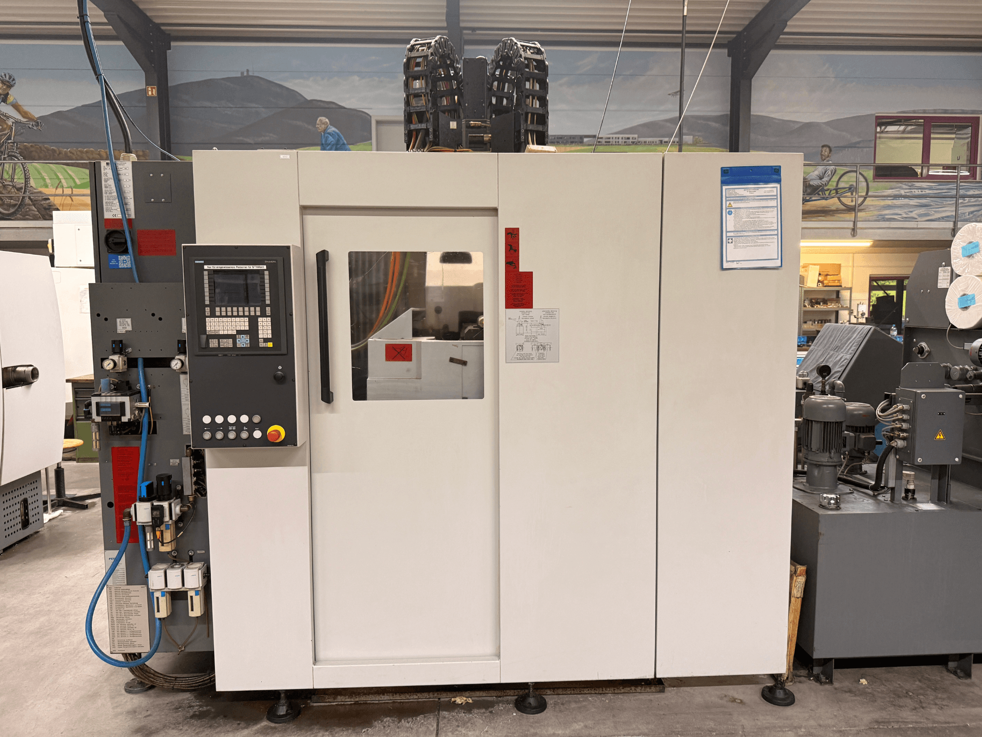 Vitt CNC-bearbetningscenter med kontrollpanel, framifrån, med knappar och digital display, i en verkstadsmiljö.